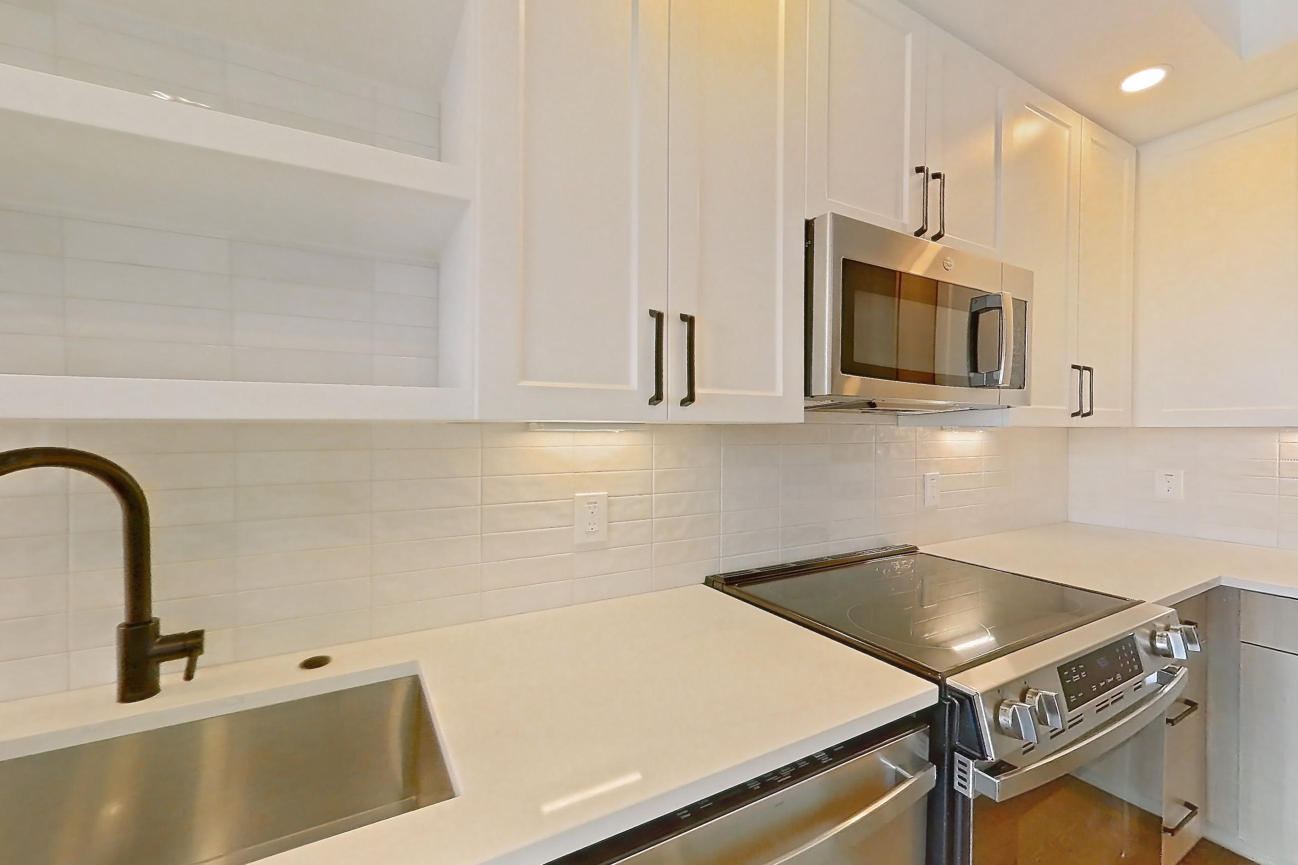 Kitchen with dishwasher, light stone countertops, light wood-finish flooring, and stainless steel appliances, Apartment 412 at The Watson