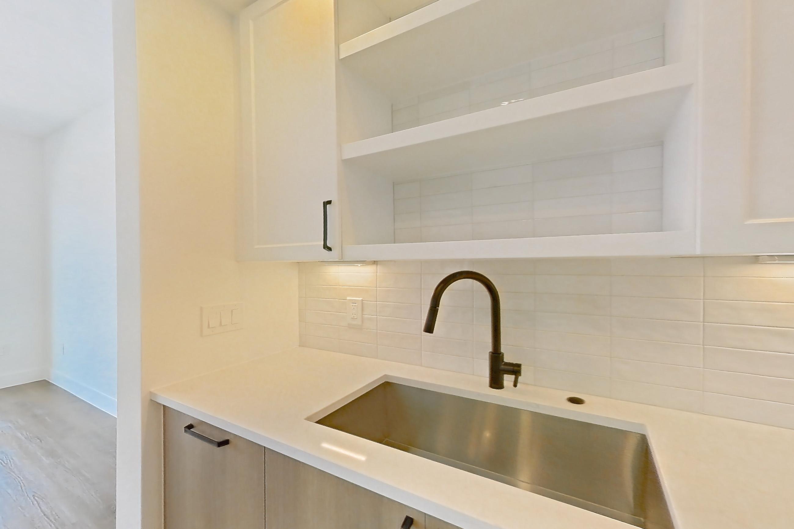 Kitchen with dishwasher, light stone countertops, light wood-finish flooring, and stainless steel appliances, Apartment 412 at The Watson
