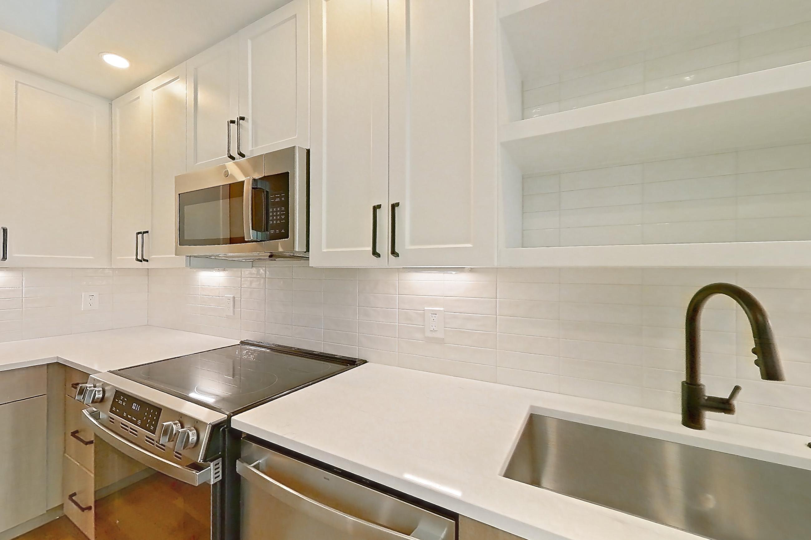 Kitchen with dishwasher, light stone countertops, light wood-finish flooring, and stainless steel appliances, Apartment 413 at The Watson