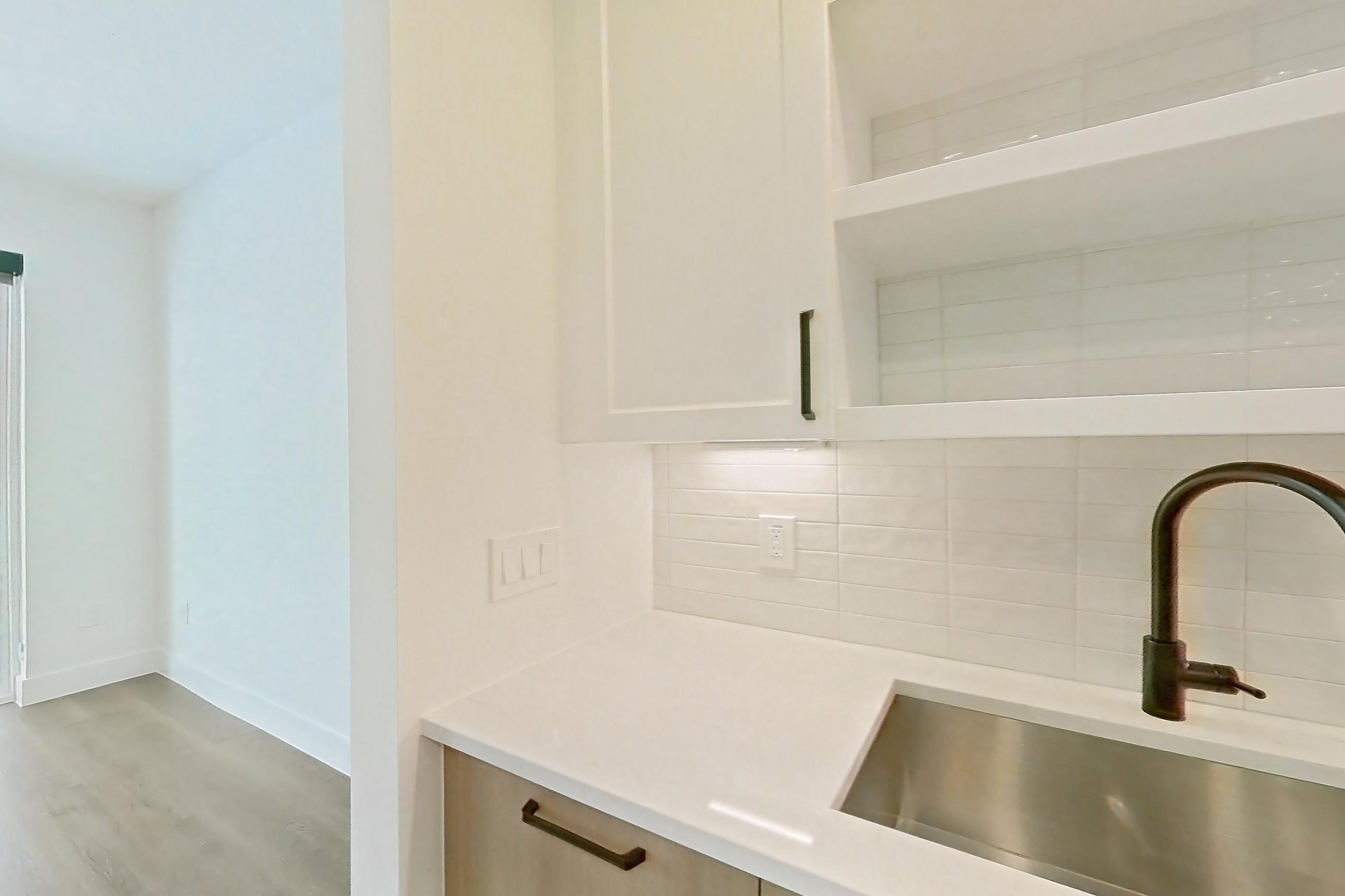 Kitchen with light stone countertops and light wood-finish flooring, Apartment 415 at The Watson