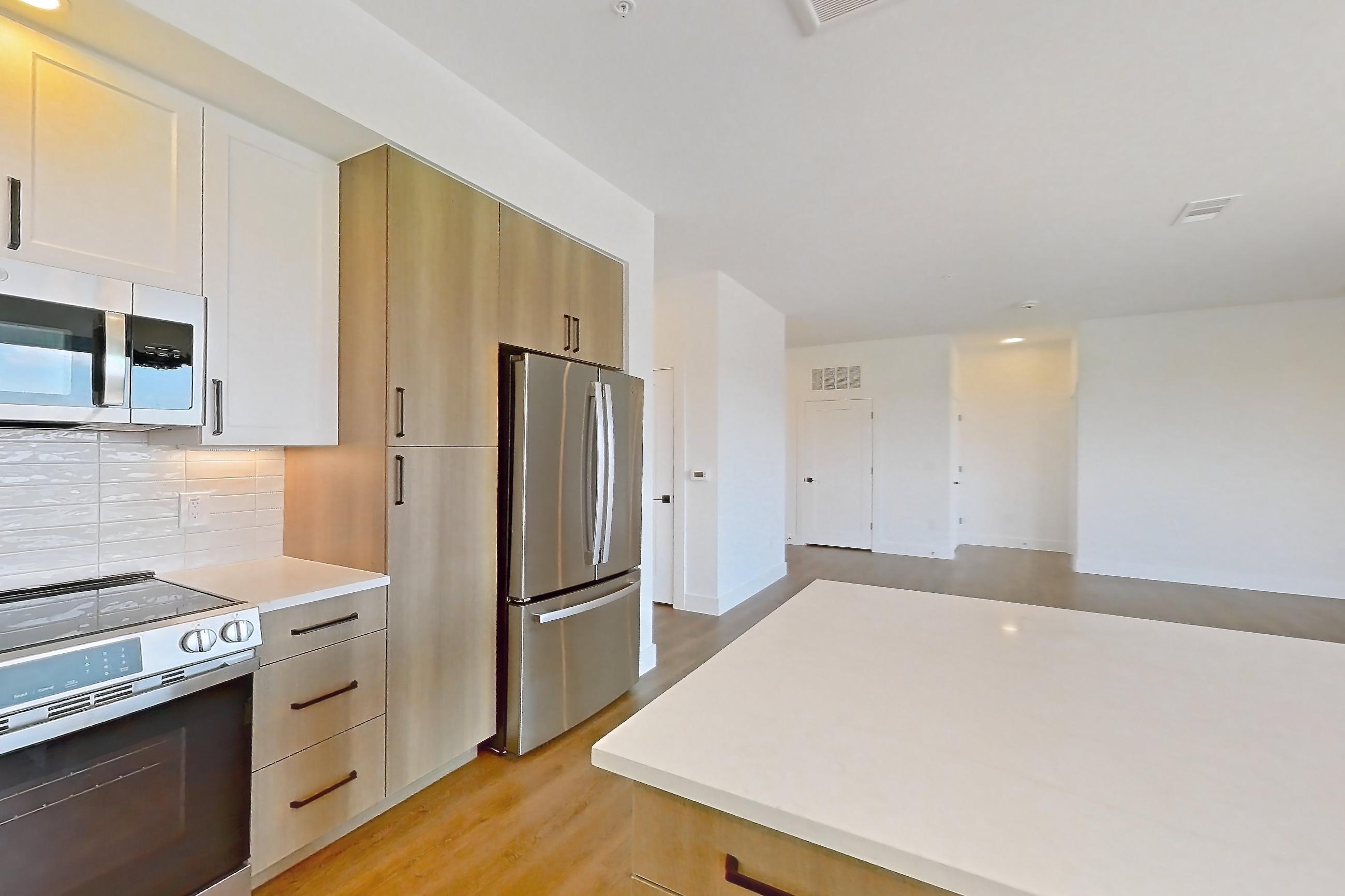 Kitchen with dishwasher, light stone countertops, light wood-finish flooring, refrigerator, and stainless steel appliances, Apartment 416 at The Watson