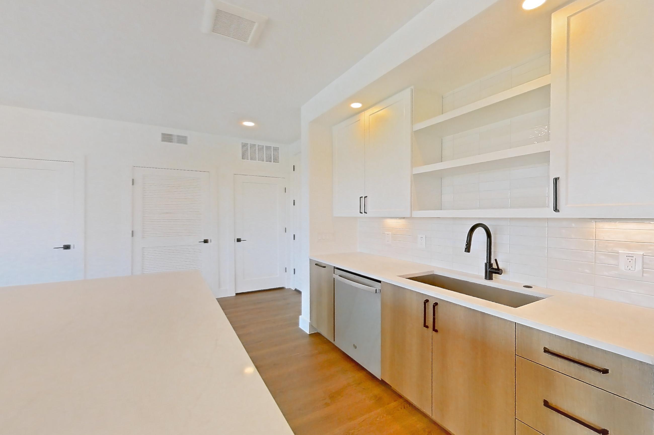 Kitchen with dishwasher, light countertops, light stone countertops, light wood-finish flooring, refrigerator, and stainless steel appliances, Apartment 502 at The Watson