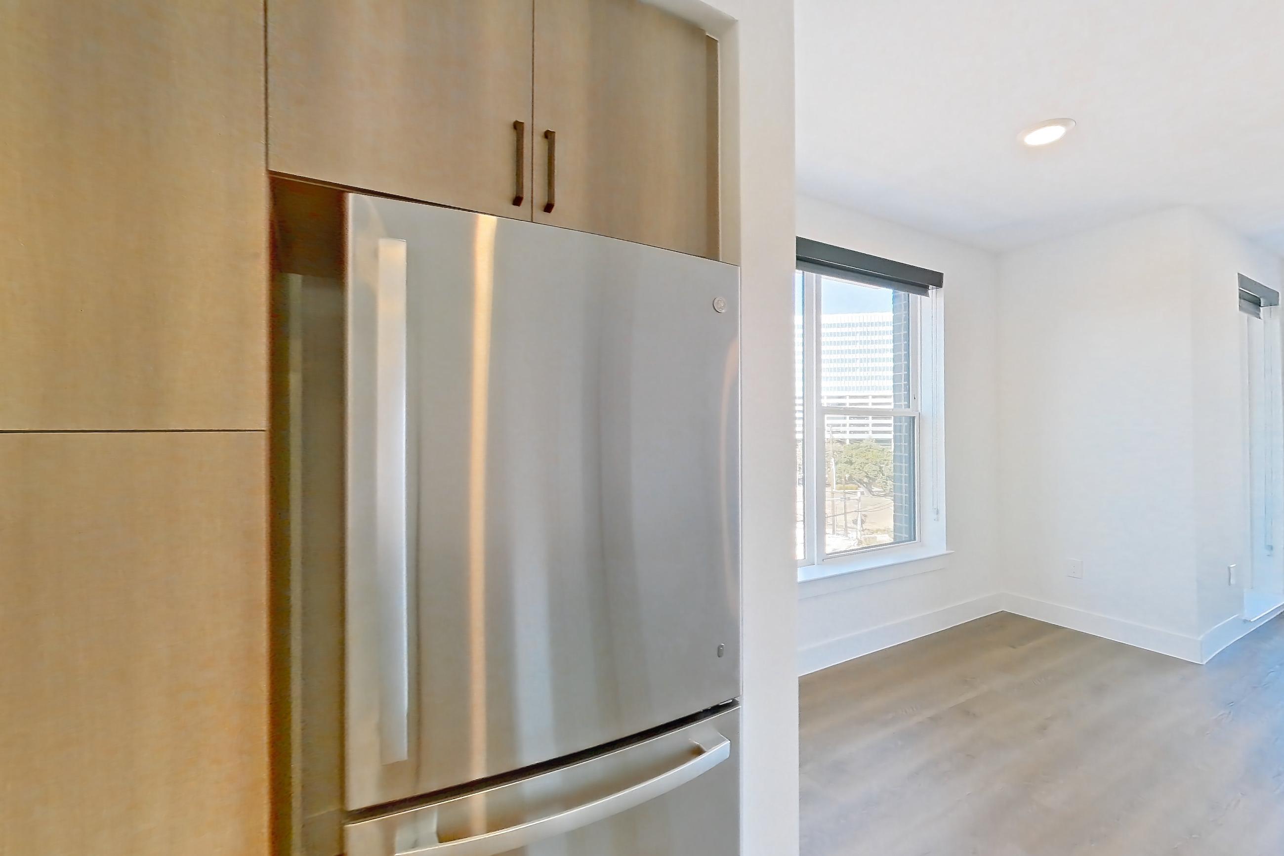 Kitchen with dishwasher, light countertops, light stone countertops, light wood-finish flooring, refrigerator, and stainless steel appliances, Apartment 502 at The Watson