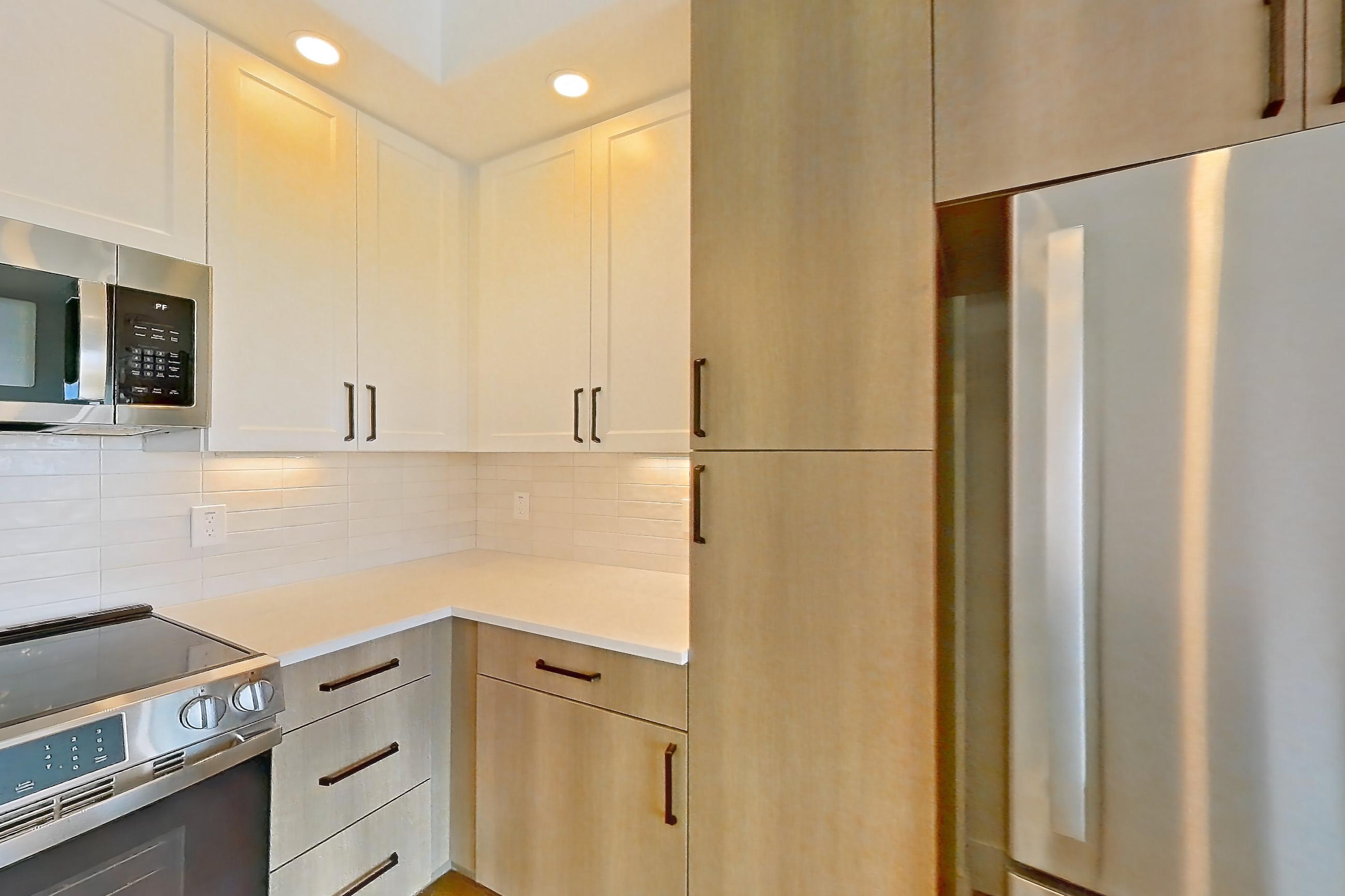 Kitchen with dishwasher, light countertops, light stone countertops, light wood-finish flooring, refrigerator, and stainless steel appliances, Apartment 502 at The Watson