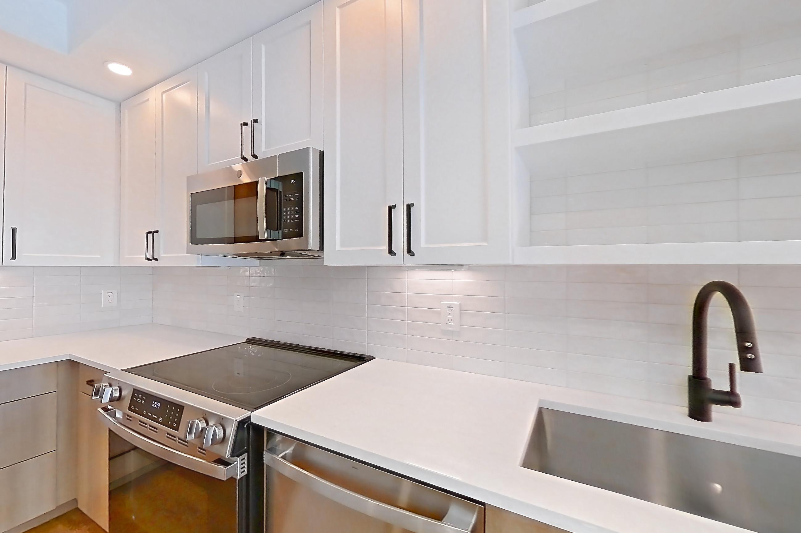 Kitchen with dishwasher, light stone countertops, light wood-finish flooring, and stainless steel appliances, Apartment 503 at The Watson