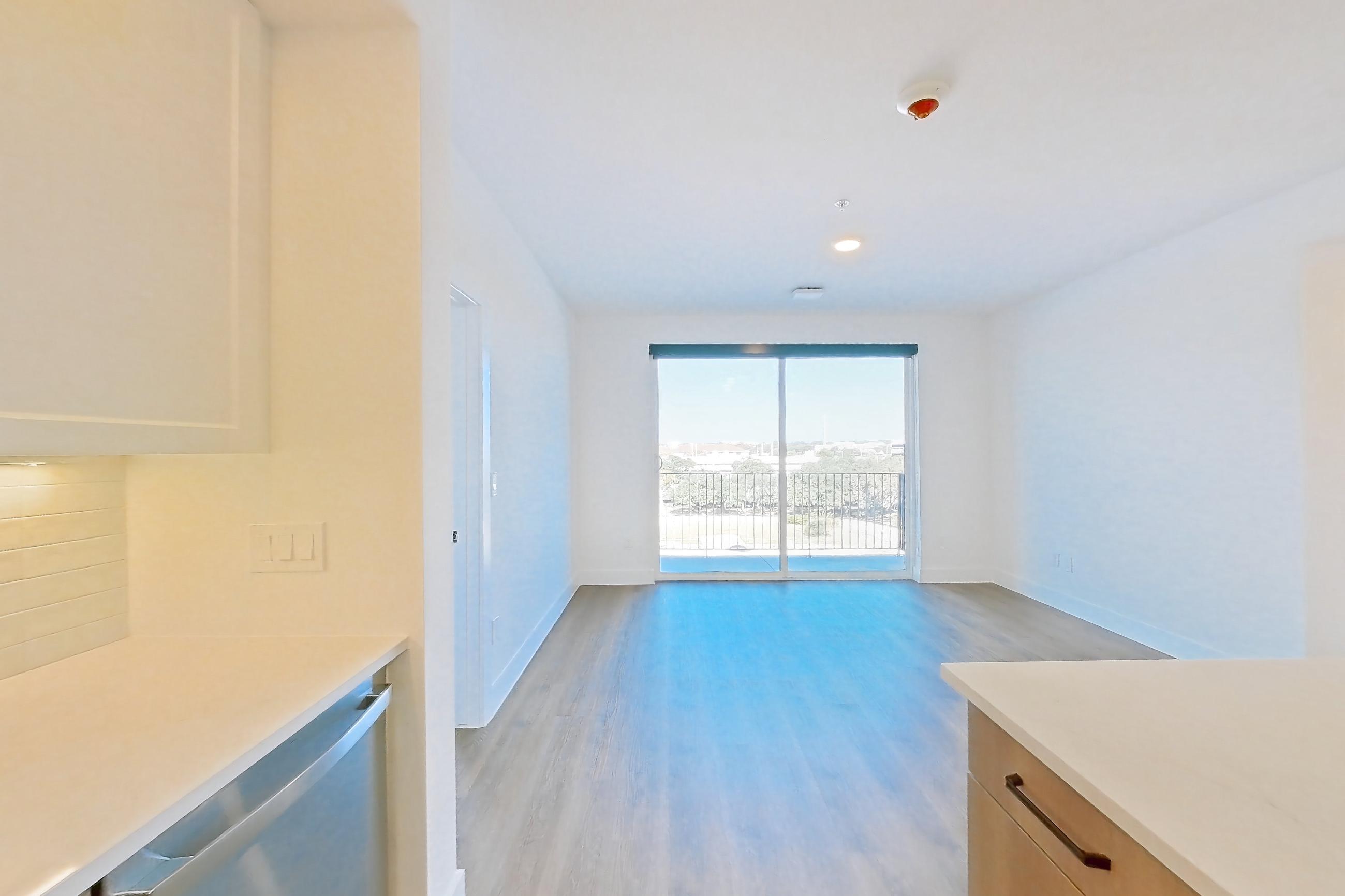 Kitchen with dishwasher, electric range, light stone countertops, light wood-finish flooring, and stainless steel appliances, Apartment 504 at The Watson