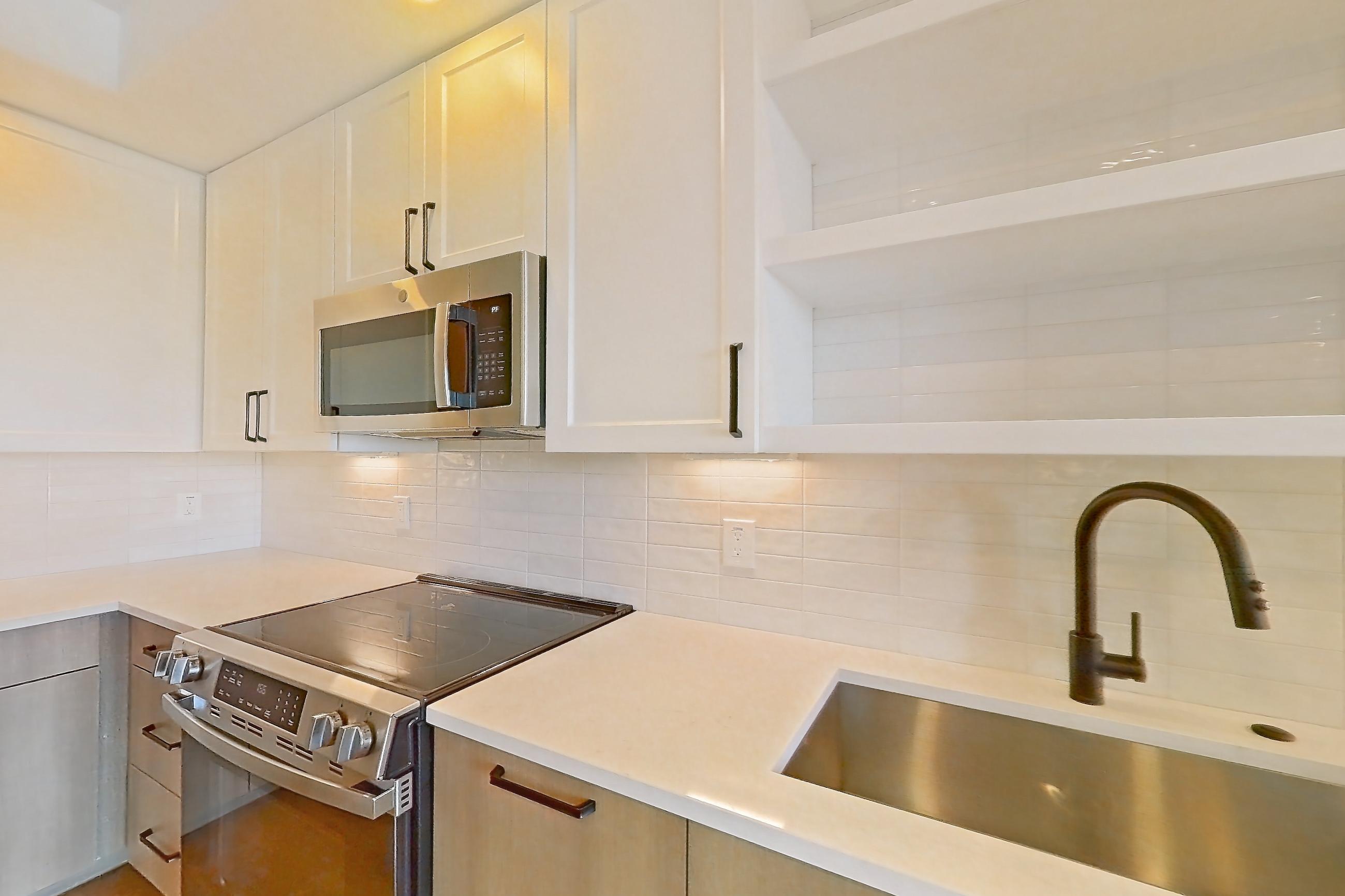 Kitchen with dishwasher, electric range, light stone countertops, light wood-finish flooring, and stainless steel appliances, Apartment 504 at The Watson