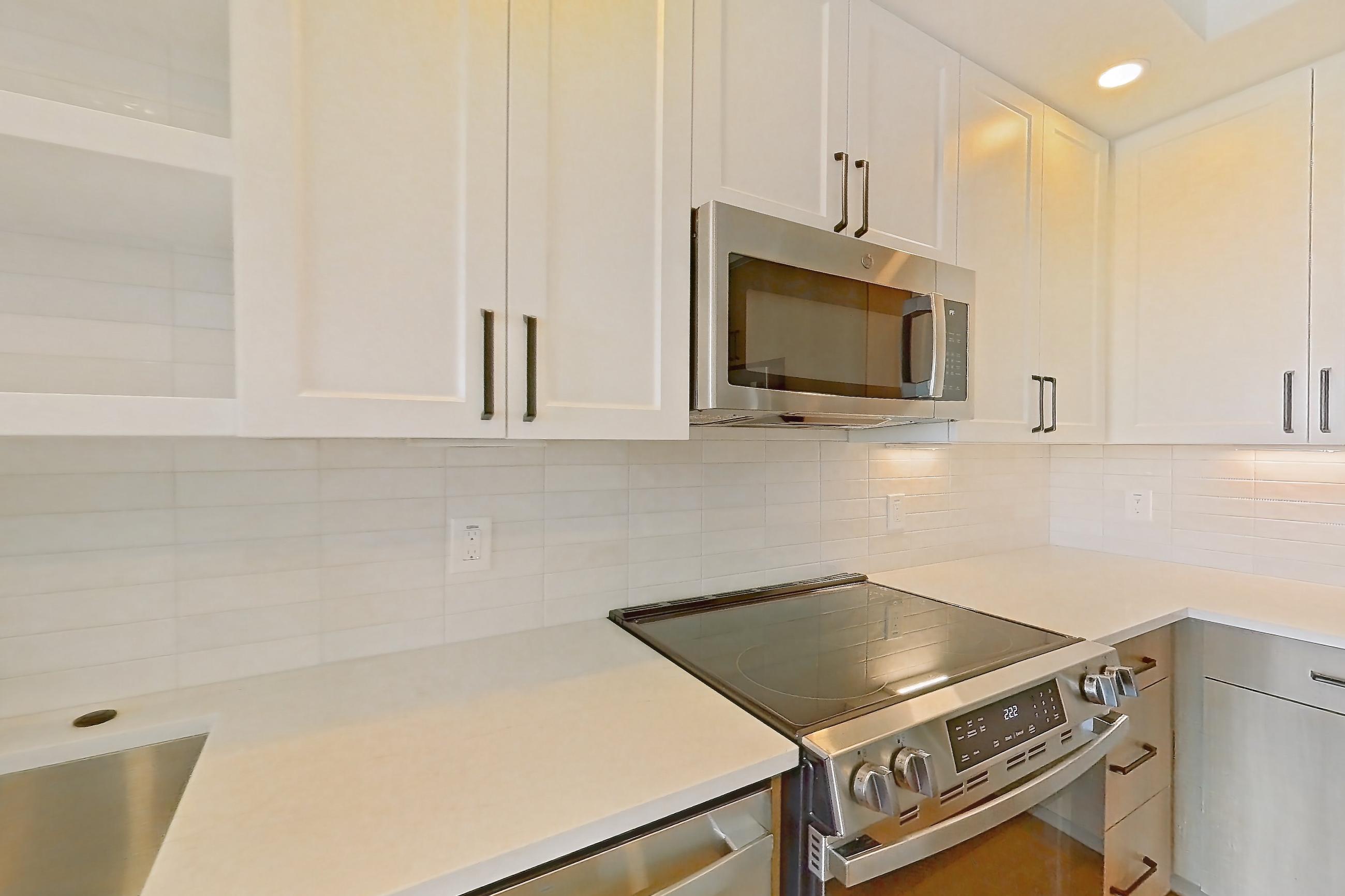 Kitchen with dishwasher, electric range, light stone countertops, light wood-finish flooring, oven/range, and stainless steel appliances, Apartment 506 at The Watson