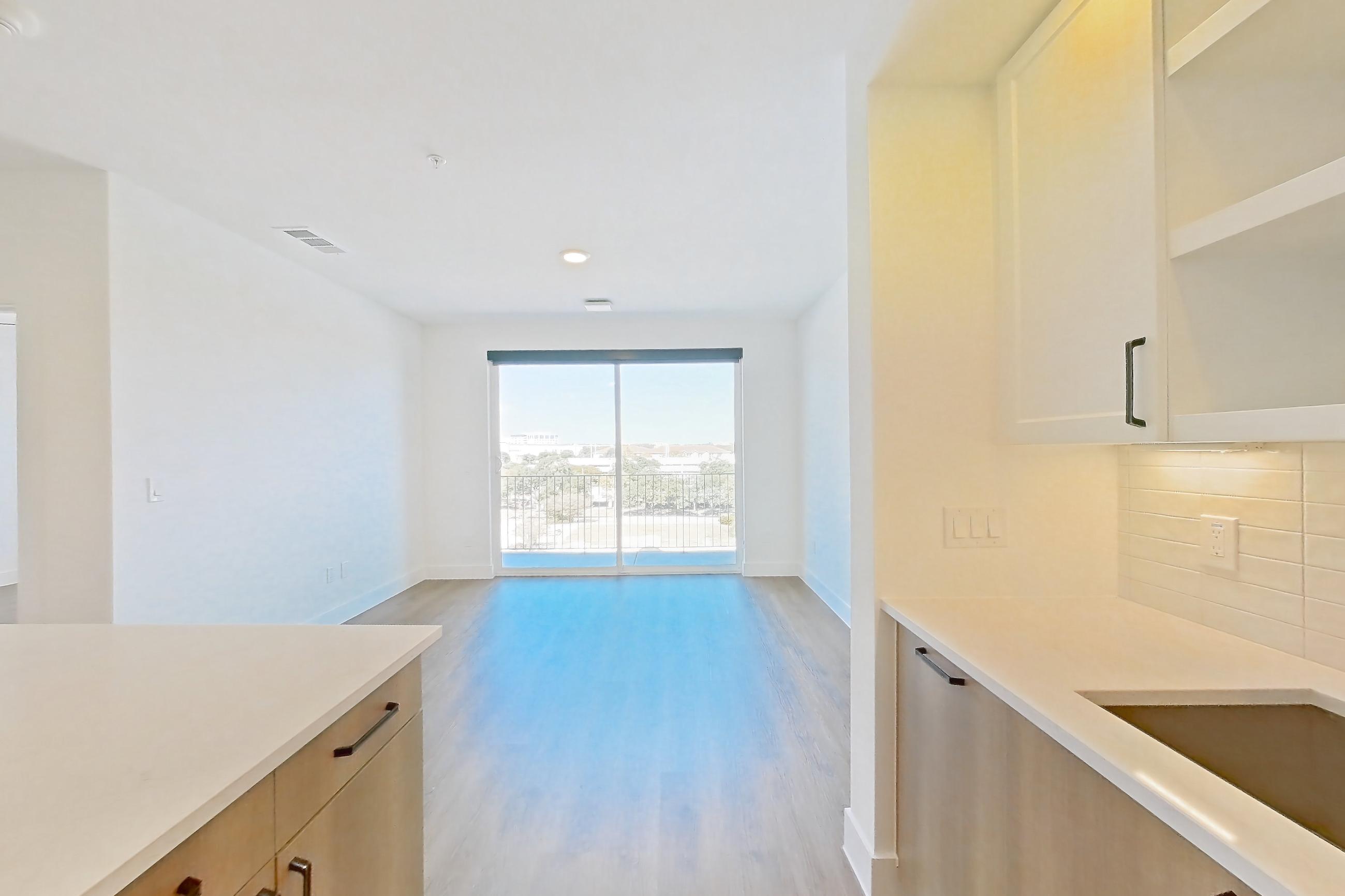 Kitchen with dishwasher, electric range, light stone countertops, light wood-finish flooring, oven/range, and stainless steel appliances, Apartment 506 at The Watson
