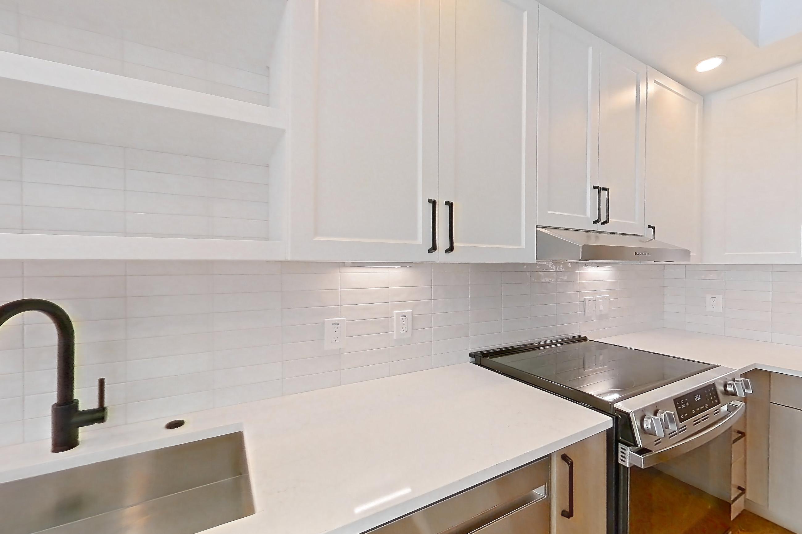 Kitchen with black appliances, dishwasher, electric range, light stone countertops, light wood-finish flooring, oven/range, and stainless steel appliances, Apartment 507 at The Watson
