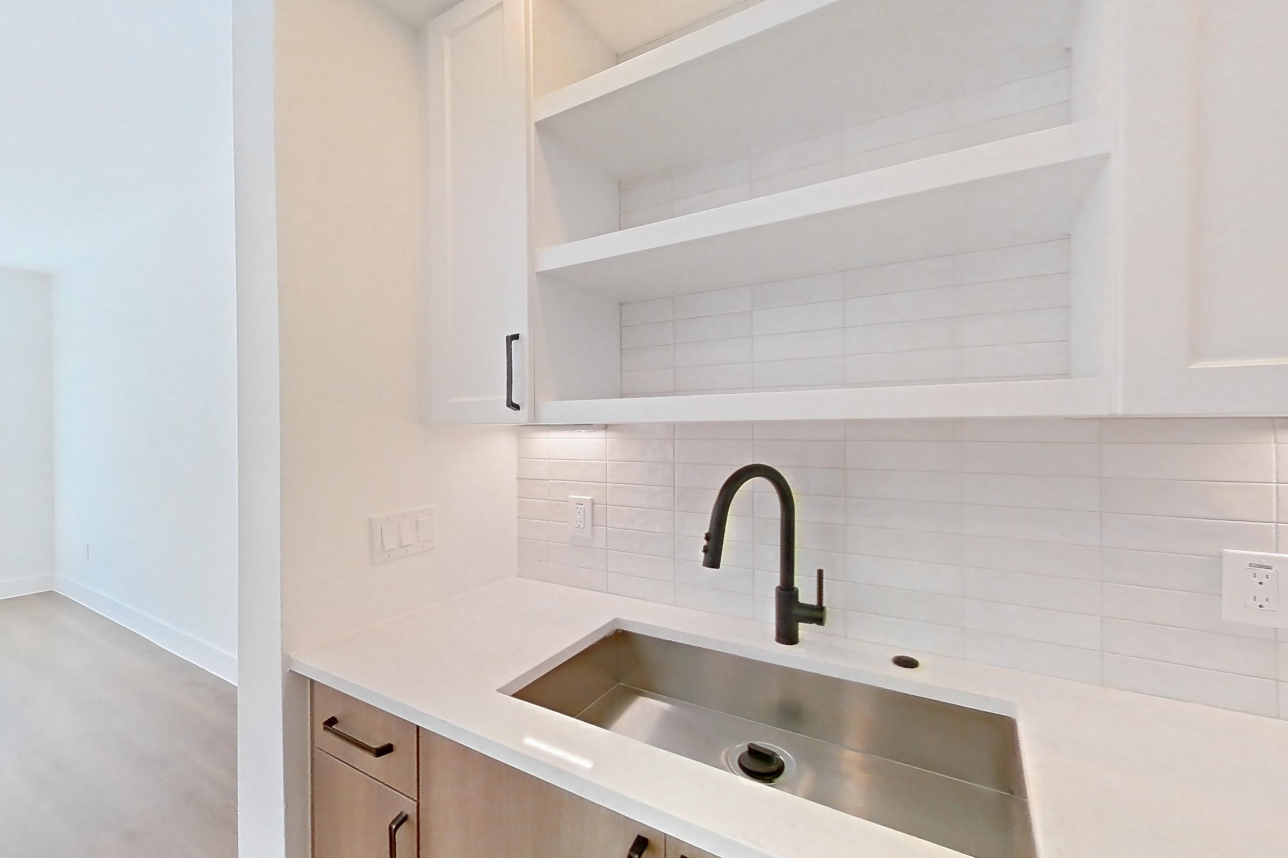 Kitchen with black appliances, dishwasher, electric range, light stone countertops, light wood-finish flooring, oven/range, and stainless steel appliances, Apartment 507 at The Watson