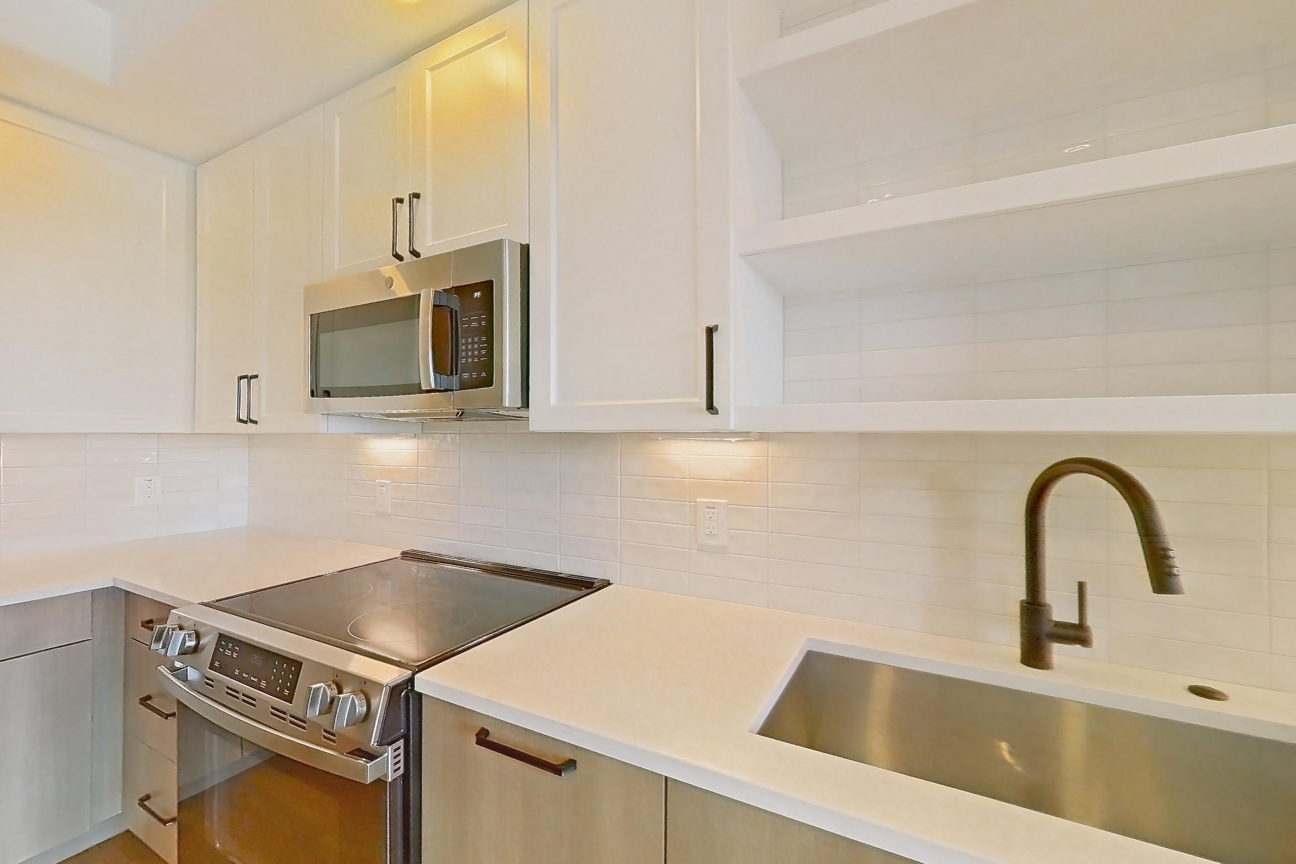 Kitchen with dishwasher, electric range, light stone countertops, light wood-finish flooring, oven/range, and stainless steel appliances, Apartment 510 at The Watson