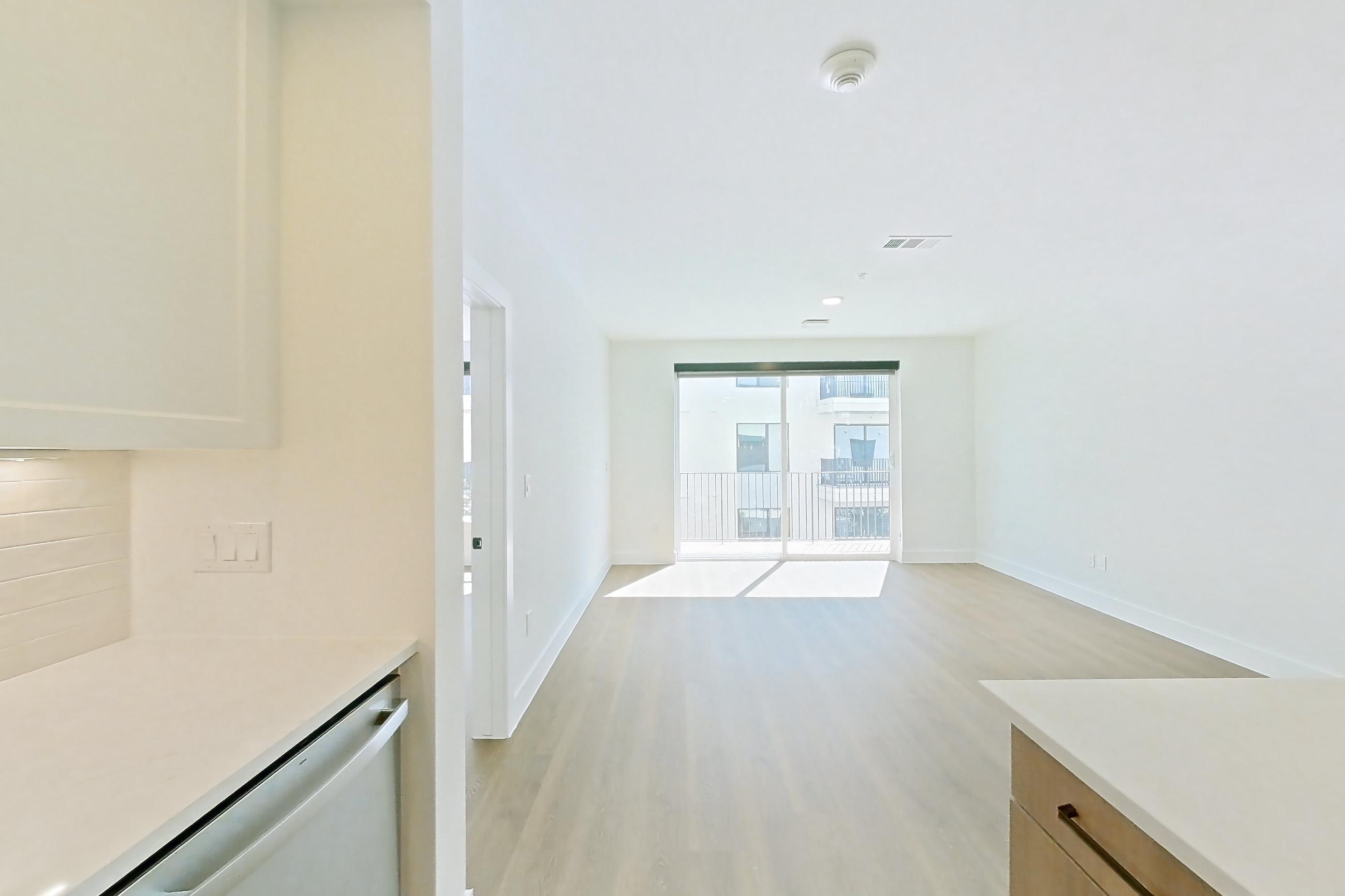 Kitchen with black appliances, dishwasher, electric range, light stone countertops, light wood-finish flooring, oven/range, and stainless steel appliances, Apartment 511 at The Watson