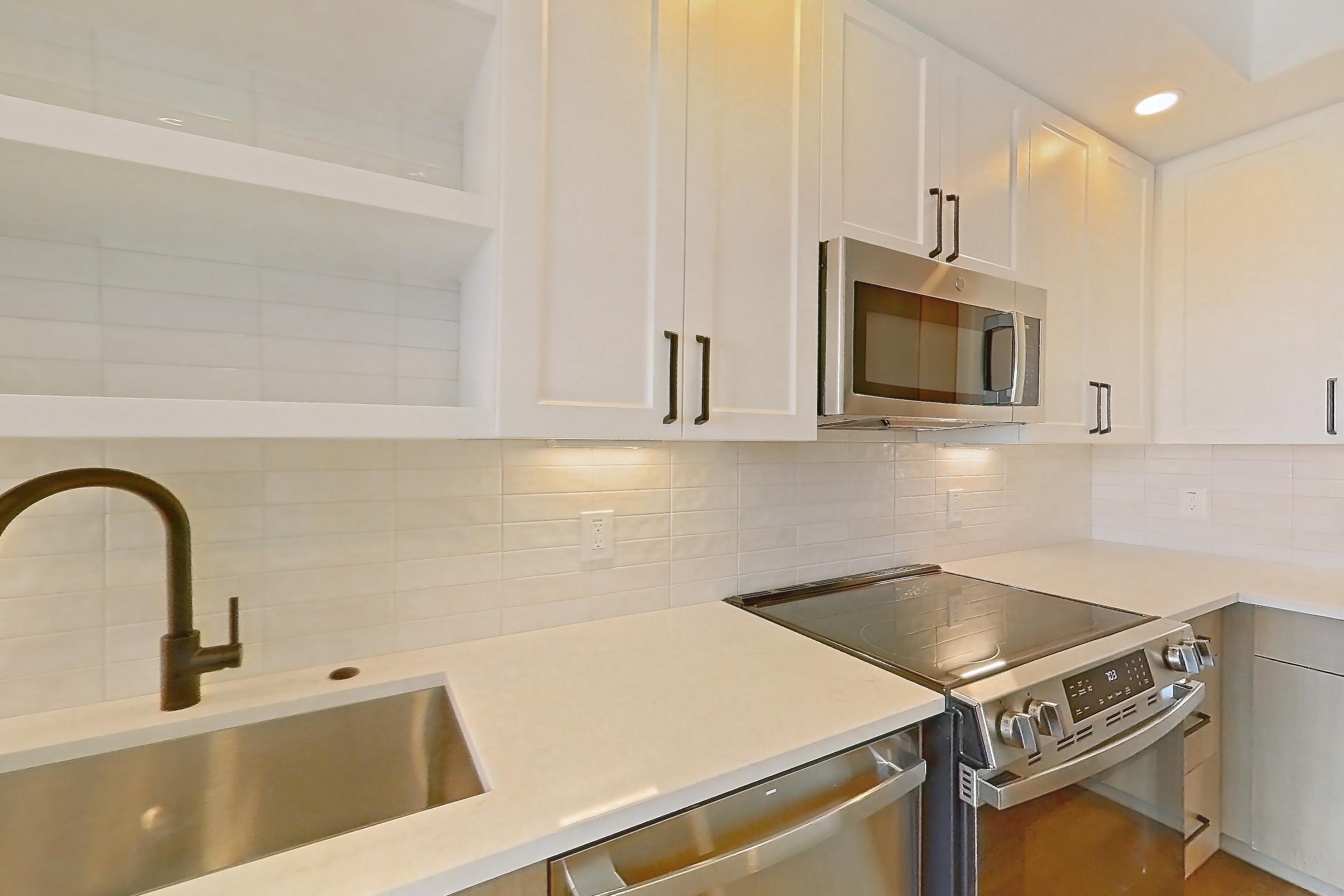 Kitchen with black appliances, dishwasher, electric range, light stone countertops, light wood-finish flooring, oven/range, and stainless steel appliances, Apartment 512 at The Watson