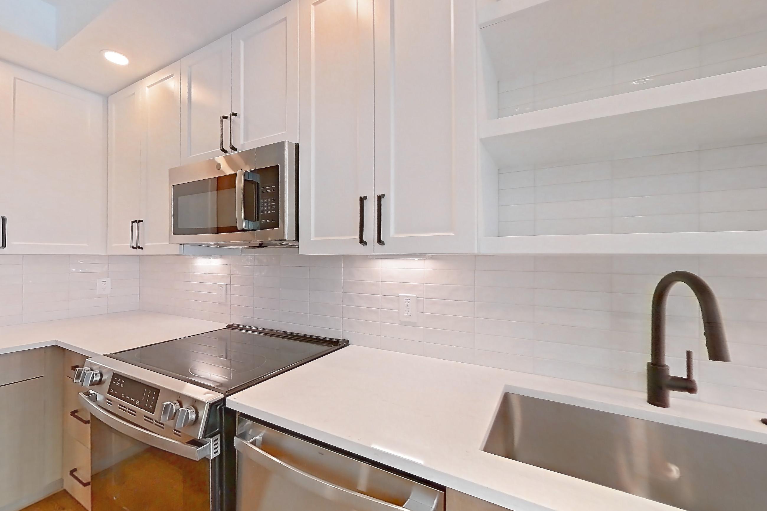 Kitchen with dishwasher, light stone countertops, light wood-finish flooring, and stainless steel appliances, Apartment 513 at The Watson
