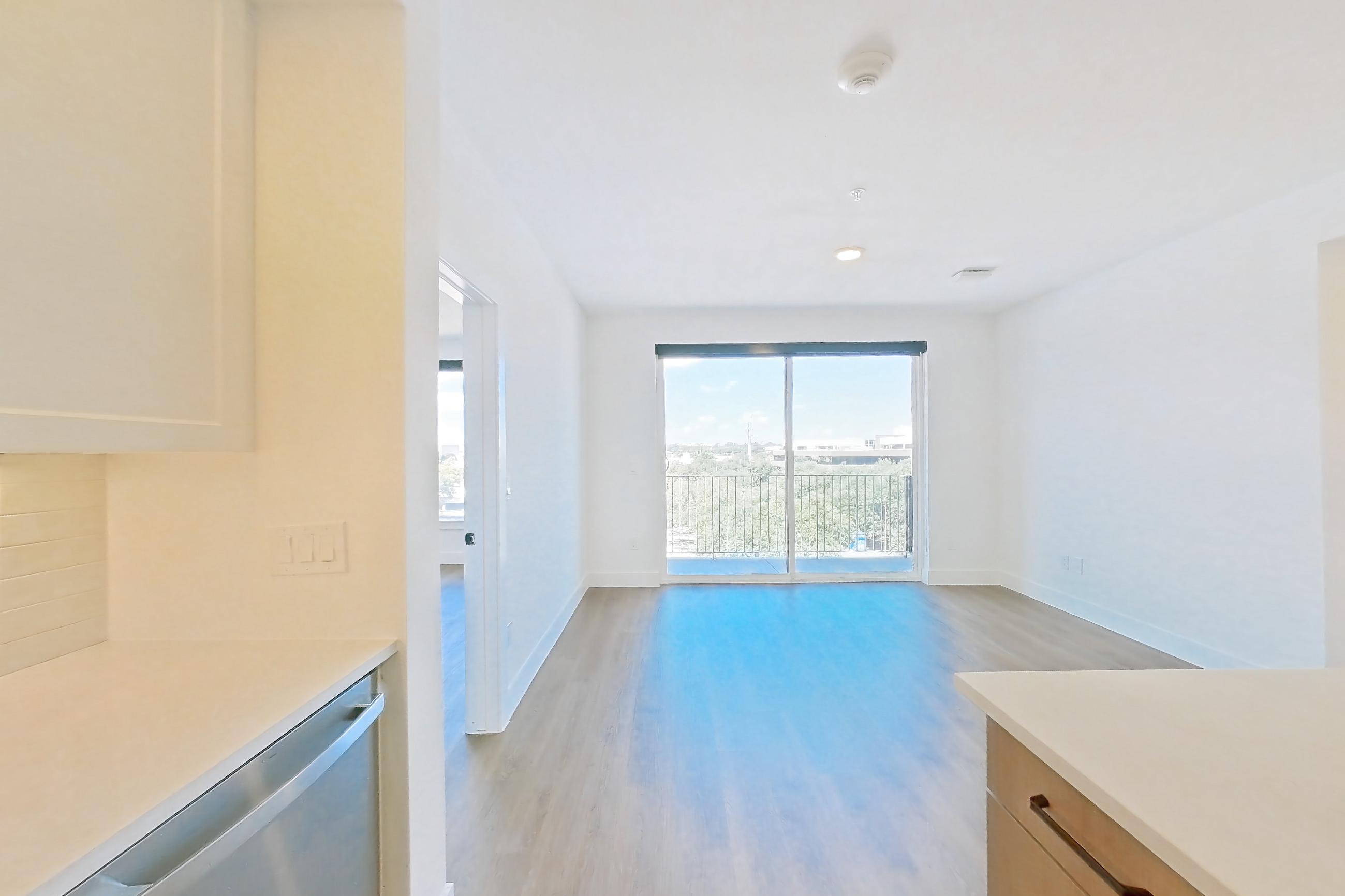 Kitchen with dishwasher, electric range, light stone countertops, light wood-finish flooring, and stainless steel appliances, Apartment 514 at The Watson