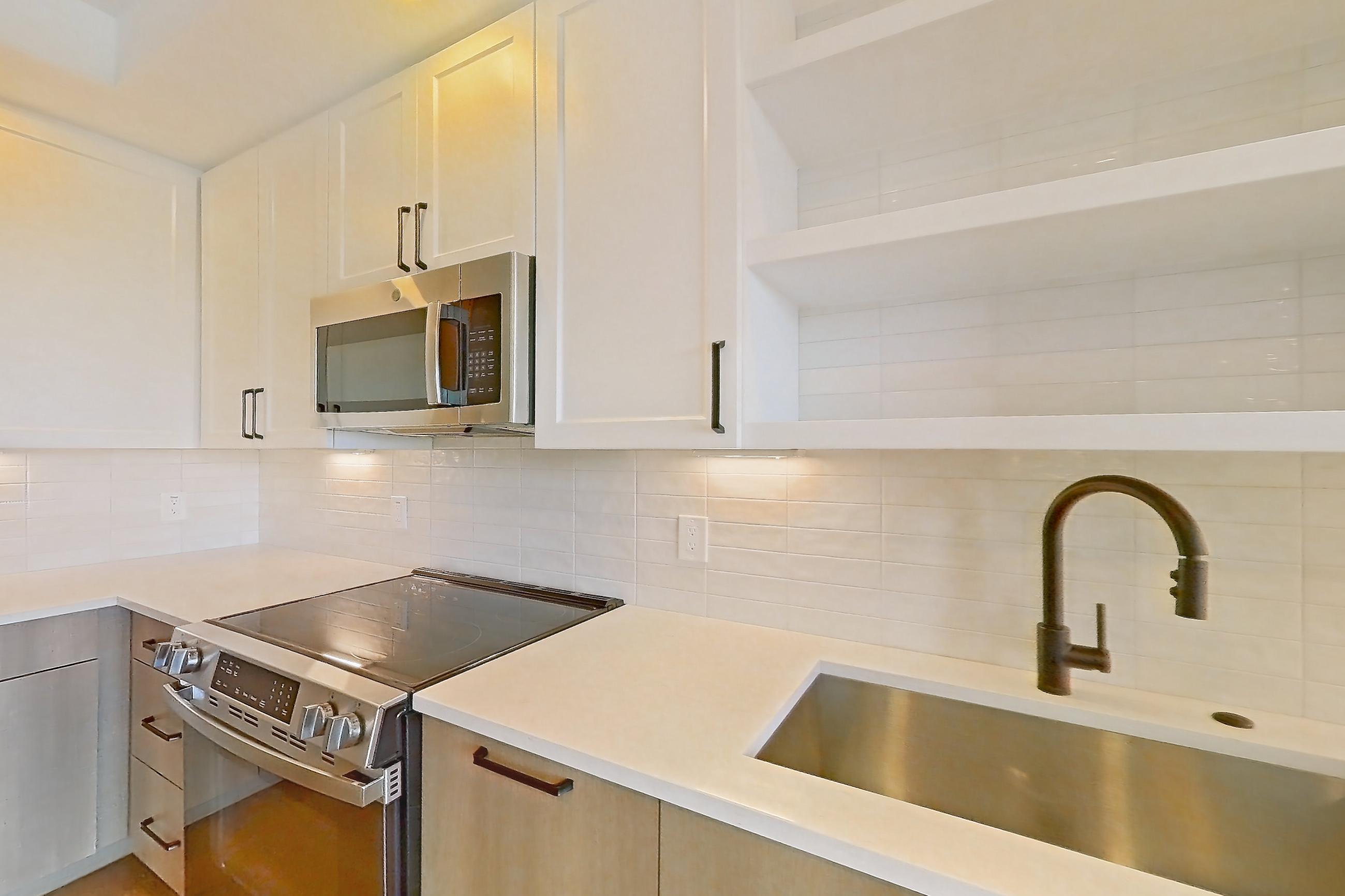 Kitchen with dishwasher, electric range, light stone countertops, light wood-finish flooring, and stainless steel appliances, Apartment 514 at The Watson