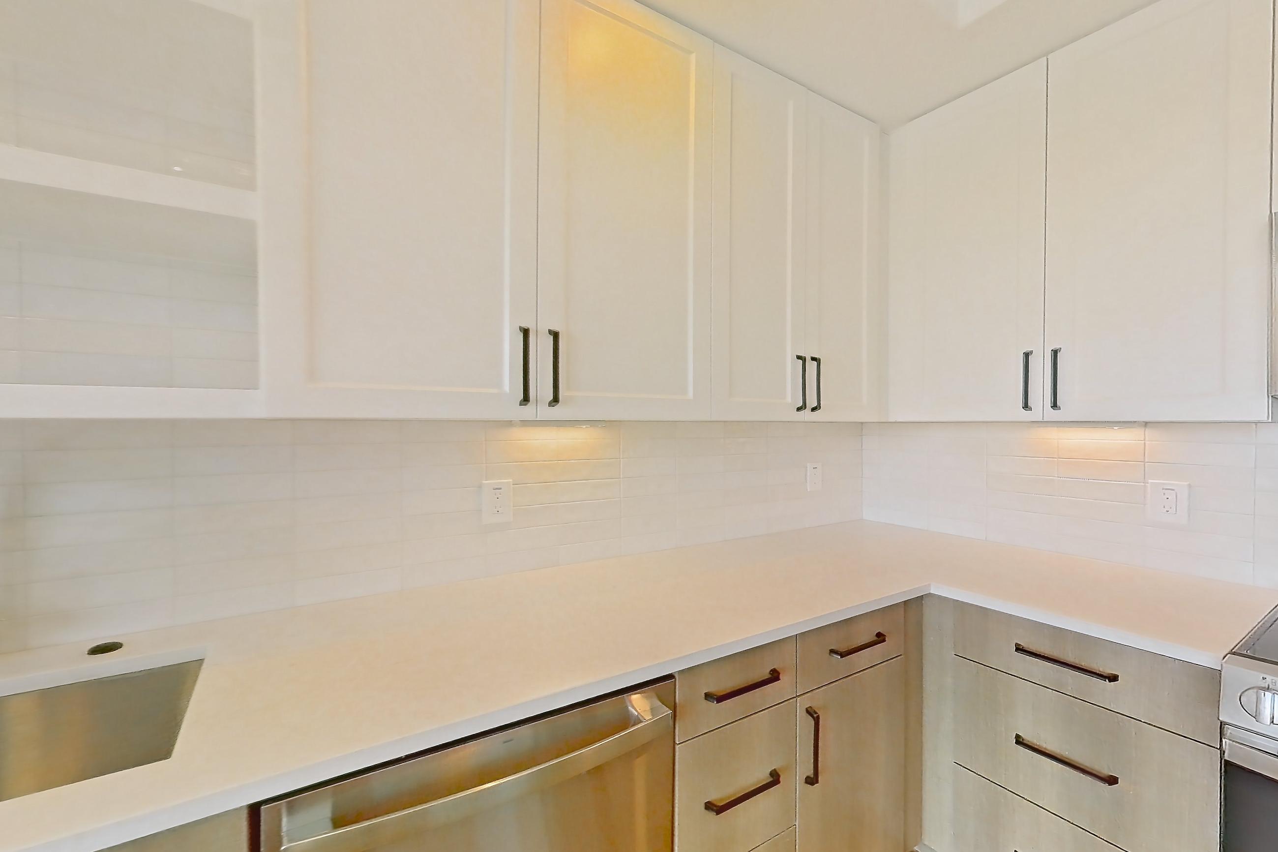 Kitchen with dishwasher, light stone countertops, light wood-finish flooring, refrigerator, and stainless steel appliances, Apartment 516 at The Watson