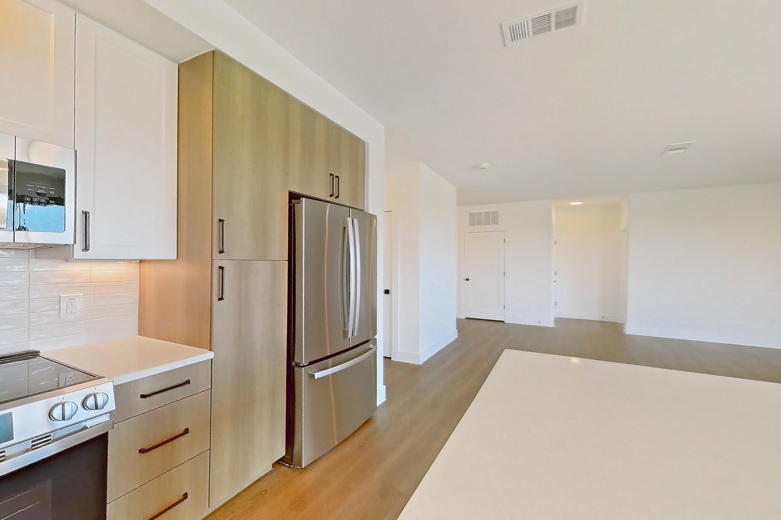 Kitchen with dishwasher, light stone countertops, light wood-finish flooring, refrigerator, and stainless steel appliances, Apartment 516 at The Watson