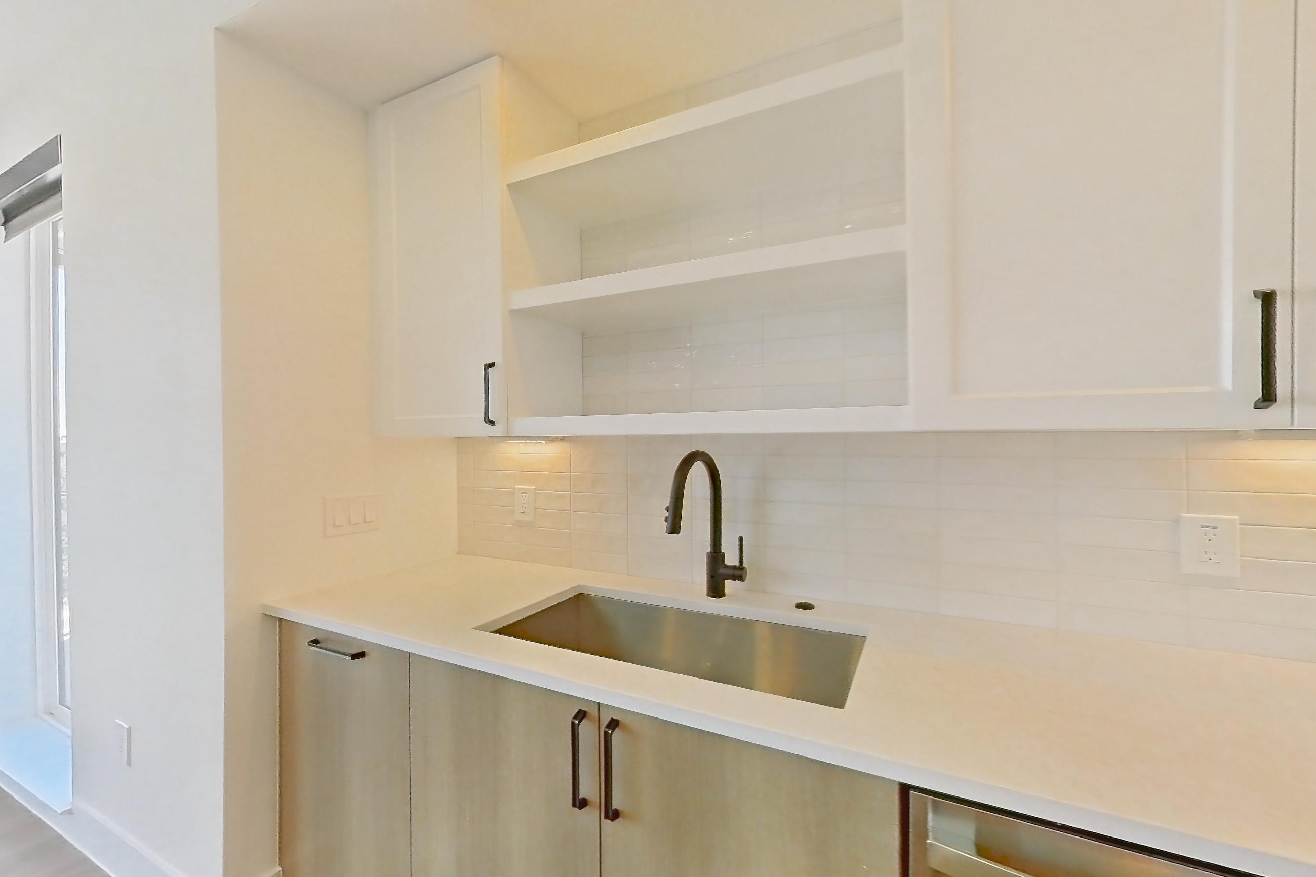 Kitchen with dishwasher, light stone countertops, light wood-finish flooring, refrigerator, and stainless steel appliances, Apartment 516 at The Watson