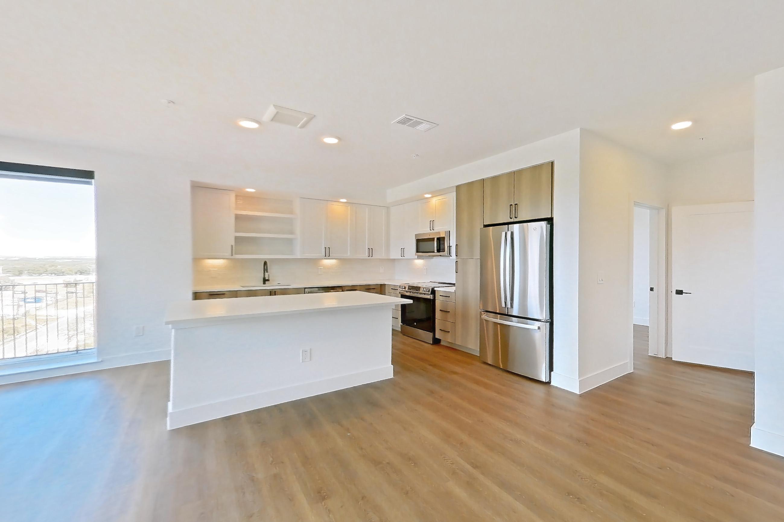 Living space with dark wood-finish flooring, electric range, light countertops, light wood-finish flooring, oven/range, and stainless steel appliances, Apartment 516 at The Watson
