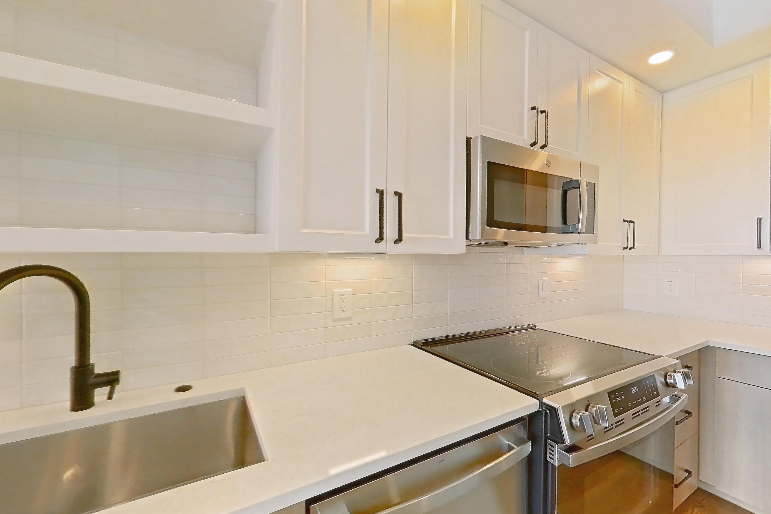 Kitchen with dishwasher, electric range, light stone countertops, light wood-finish flooring, and stainless steel appliances, Apartment 607 at The Watson