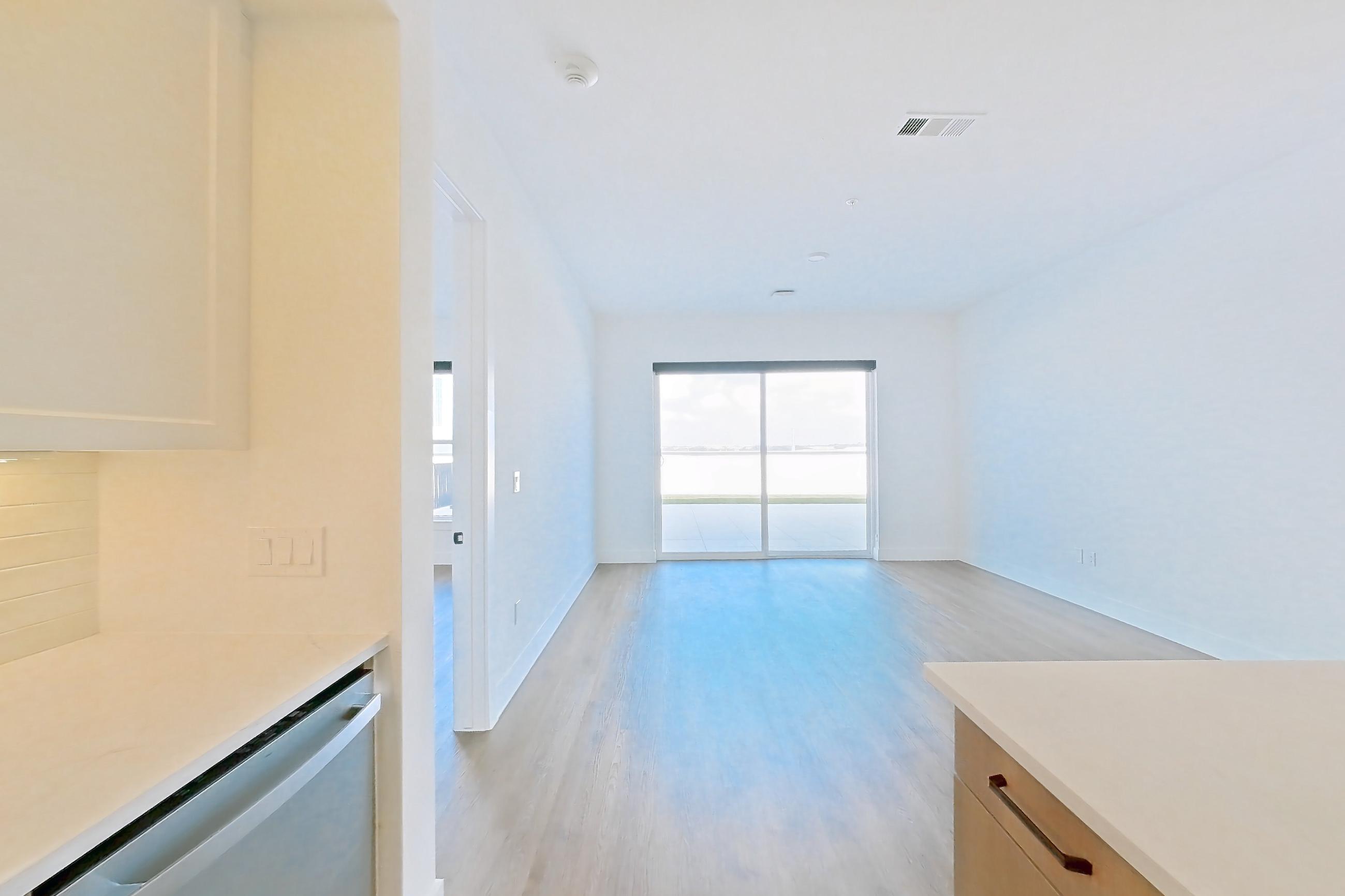 Kitchen with dishwasher, electric range, light stone countertops, light wood-finish flooring, and stainless steel appliances, Apartment 609 at The Watson