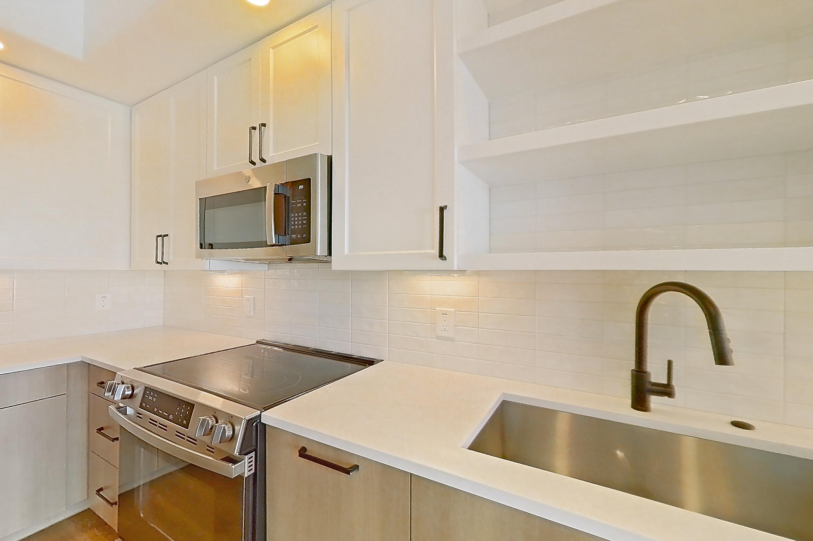 Kitchen with dishwasher, electric range, light stone countertops, light wood-finish flooring, and stainless steel appliances, Apartment 609 at The Watson