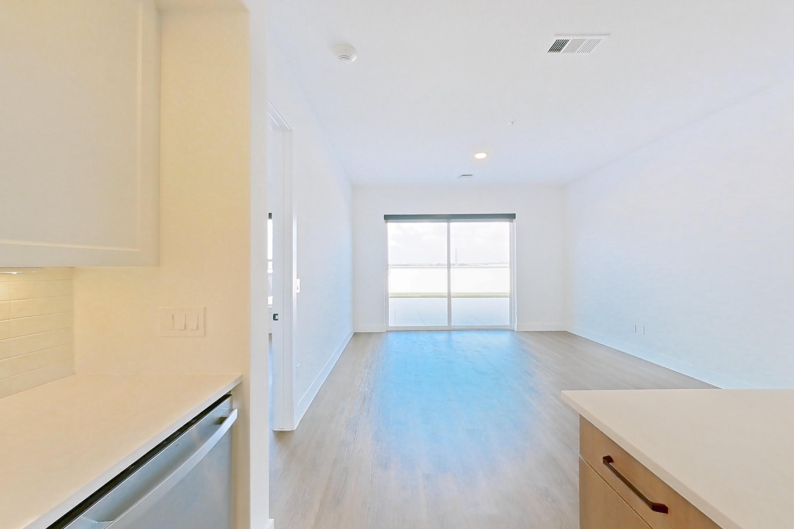 Kitchen with black appliances, dishwasher, electric range, light stone countertops, light wood-finish flooring, oven/range, and stainless steel appliances, Apartment 611 at The Watson