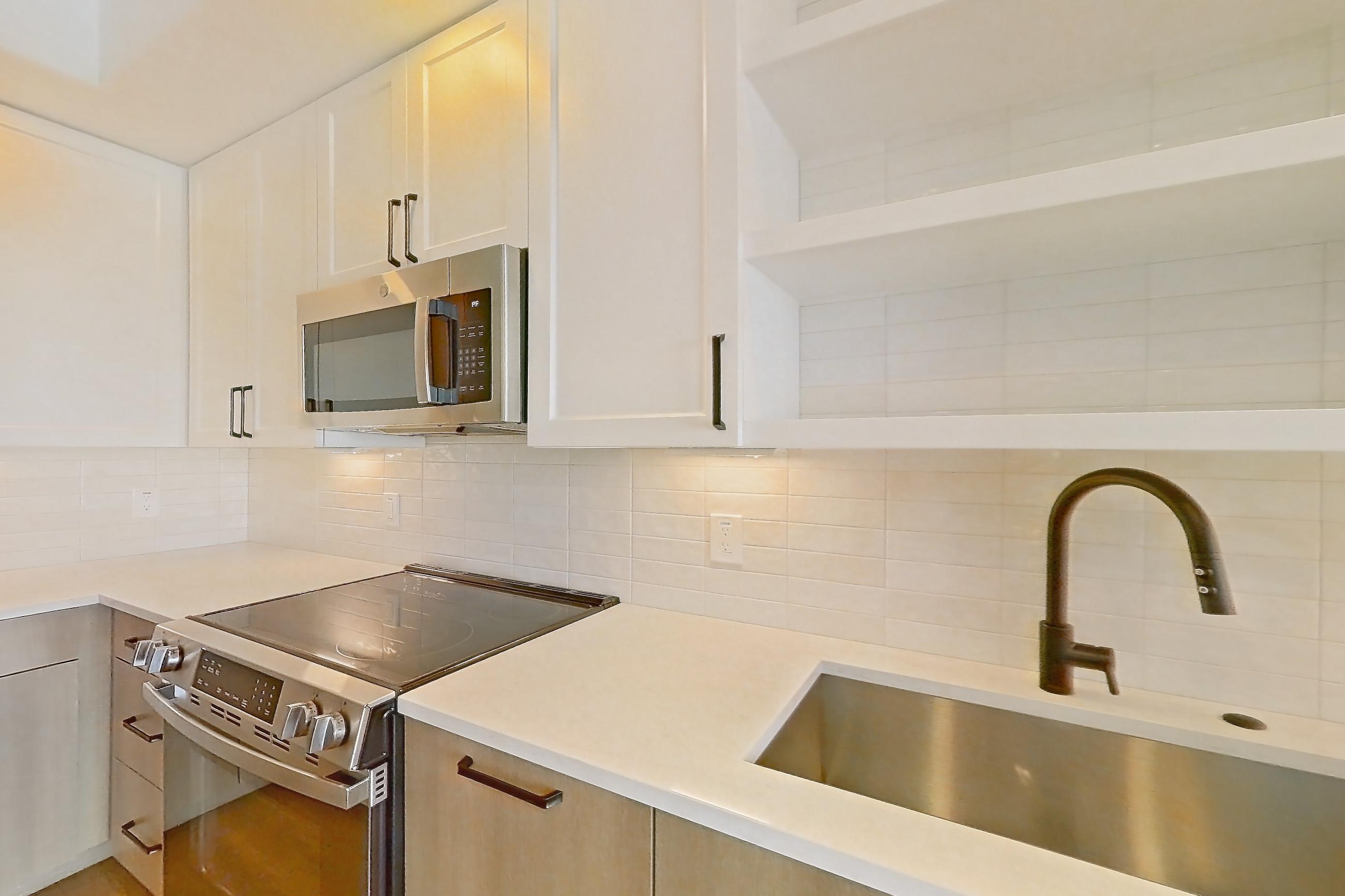 Kitchen with black appliances, dishwasher, electric range, light stone countertops, light wood-finish flooring, oven/range, and stainless steel appliances, Apartment 611 at The Watson
