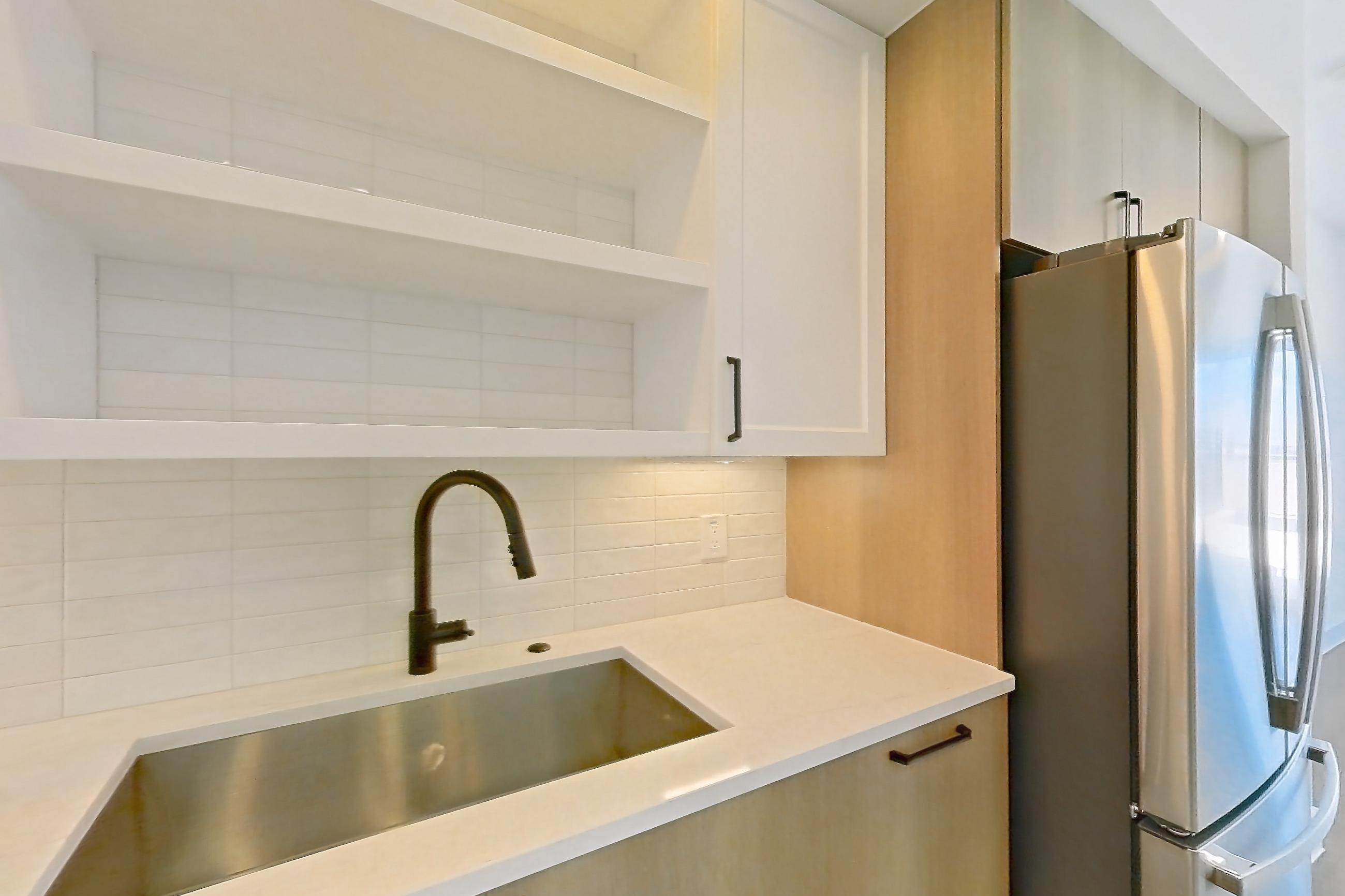 Kitchen with dishwasher, light countertops, light stone countertops, light wood-finish flooring, refrigerator, and stainless steel appliances, Apartment 615 at The Watson