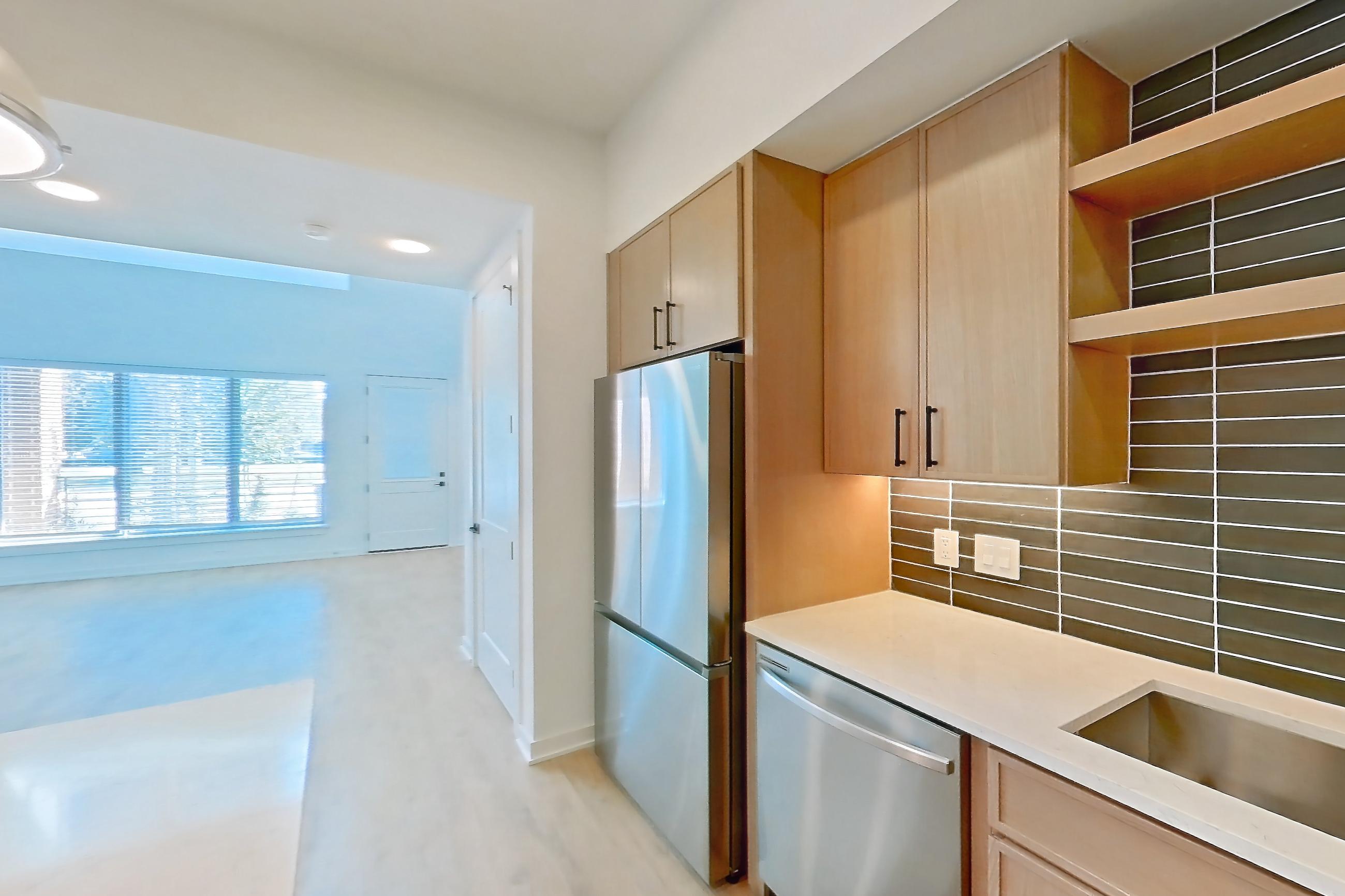 Kitchen with dishwasher, electric range, light countertops, light stone countertops, light wood-finish flooring, oven/range, refrigerator, and stainless steel appliances, Apartment 1104 at Cortland Galleria