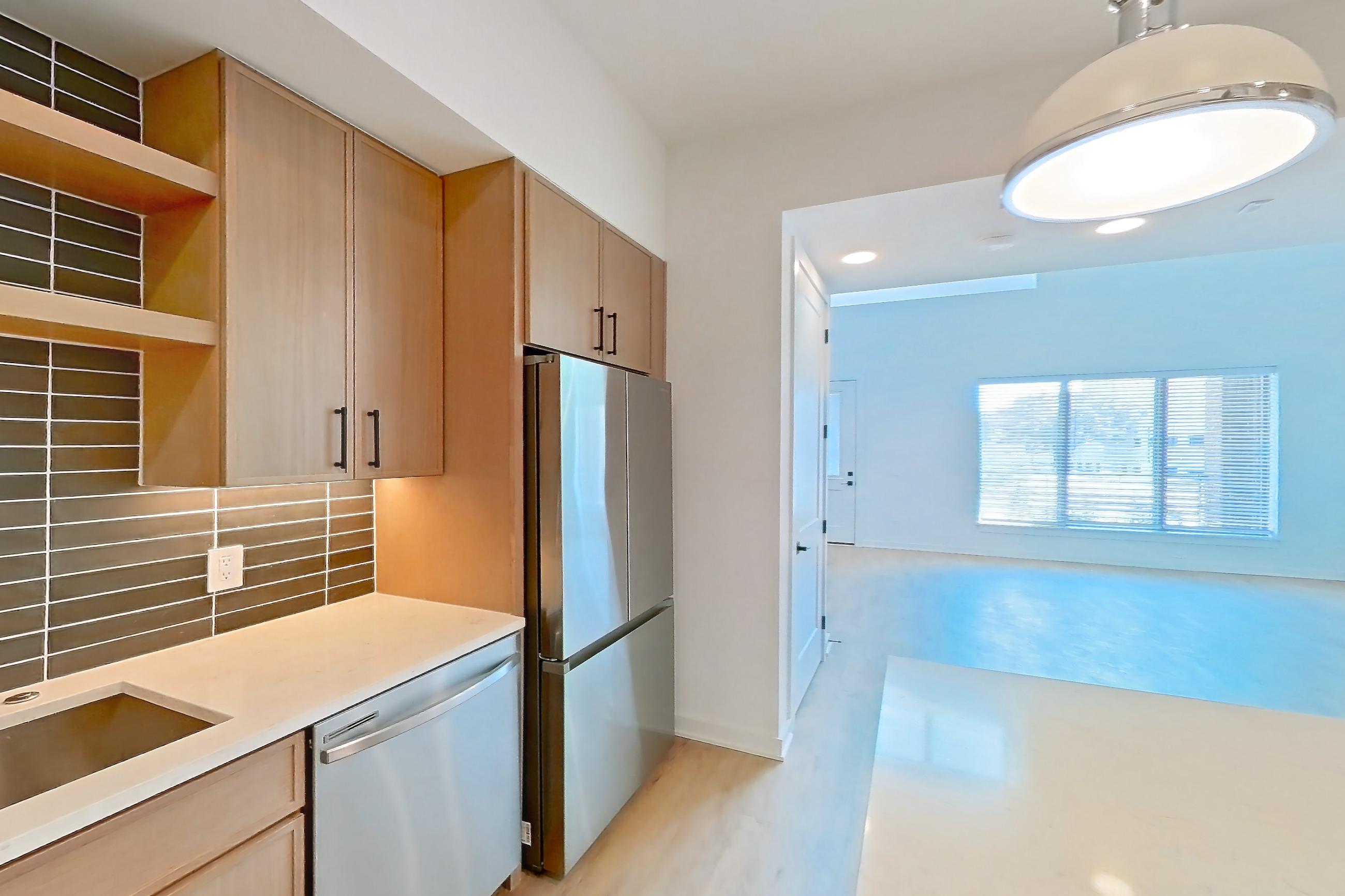 Kitchen with dishwasher, electric range, light stone countertops, light wood-finish flooring, oven/range, refrigerator, and stainless steel appliances, Apartment 1106 at Cortland Galleria
