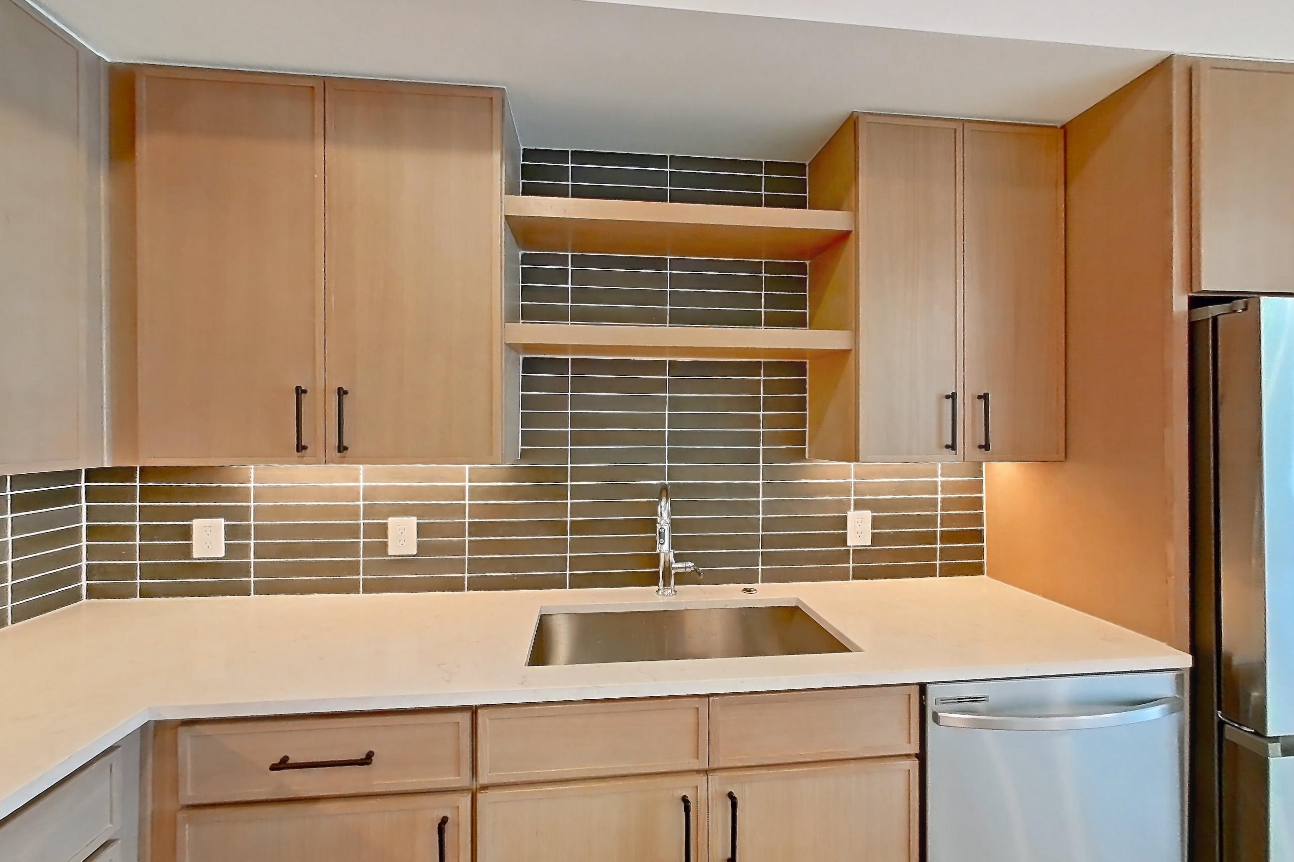 Kitchen with dishwasher, electric range, light stone countertops, light wood-finish flooring, oven/range, refrigerator, and stainless steel appliances, Apartment 1106 at Cortland Galleria