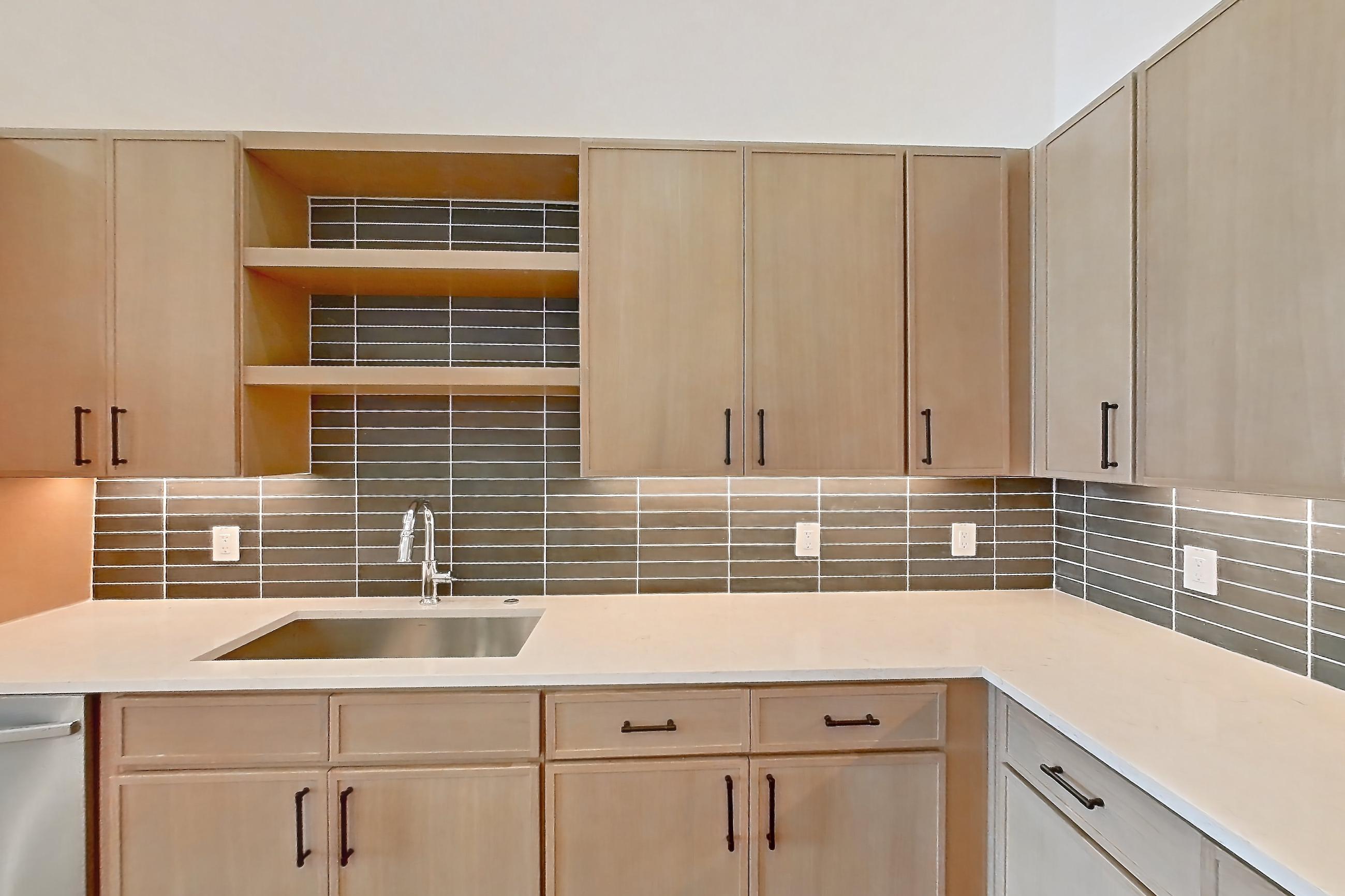 Kitchen with dishwasher, electric range, light countertops, light stone countertops, light wood-finish flooring, oven/range, refrigerator, and stainless steel appliances, Apartment 1111 at Cortland Galleria