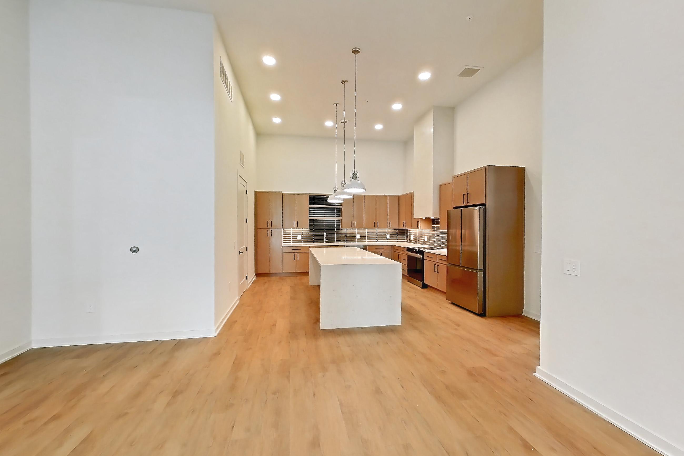 Living room with black appliances, electric range, light countertops, light wood-finish flooring, oven/range, refrigerator, and stainless steel appliances, Apartment 1114 at Cortland Galleria
