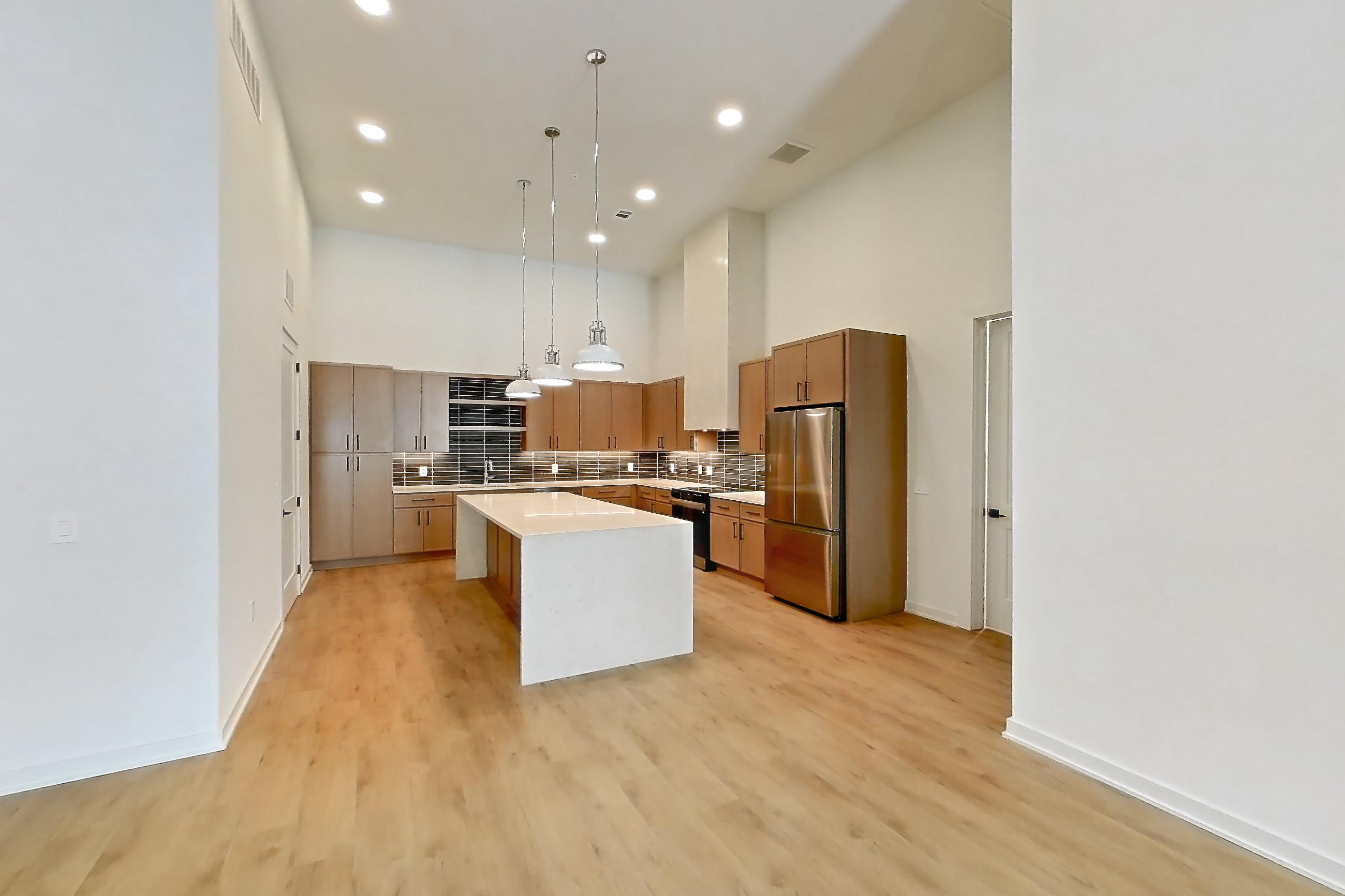 Living room with electric range, light countertops, light wood-finish flooring, refrigerator, and stainless steel appliances, Apartment 1112 at Cortland Galleria
