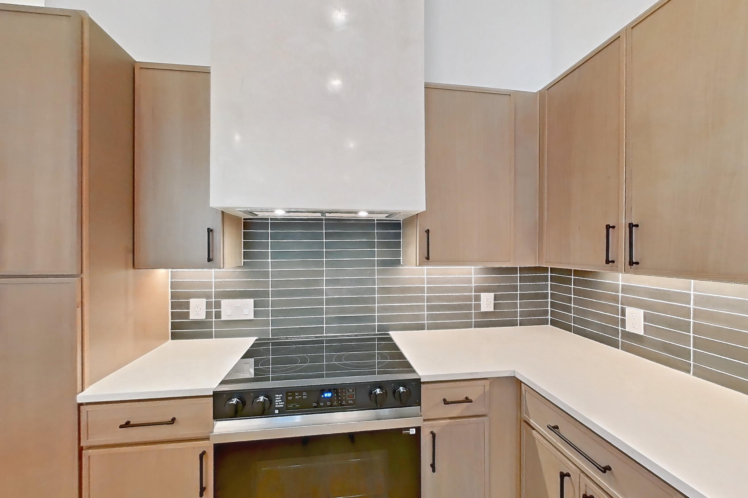 Kitchen with dishwasher, electric range, light stone countertops, light wood-finish flooring, oven/range, and stainless steel appliances, Apartment 1107 at Cortland Galleria
