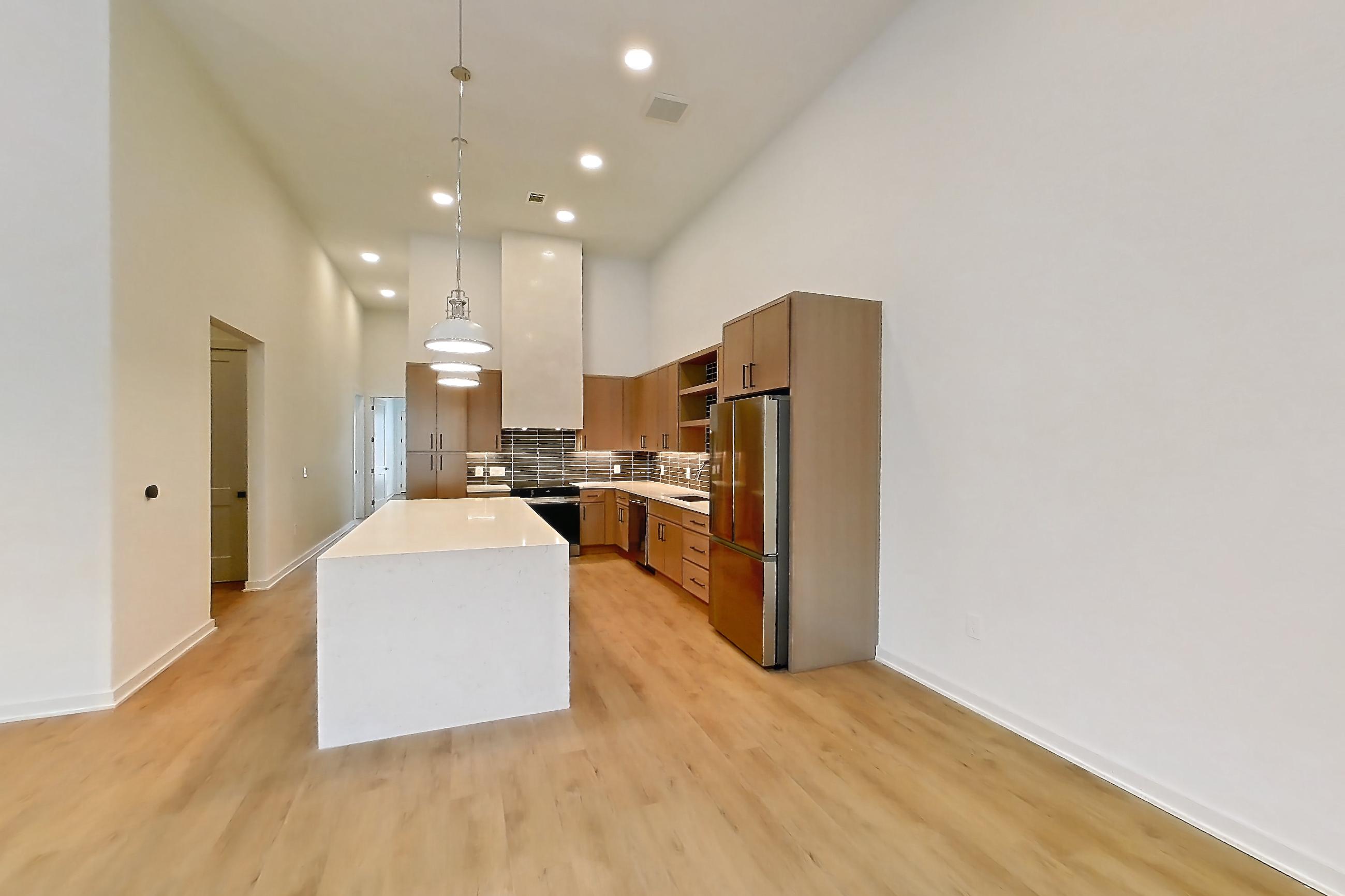 Living room with dishwasher, electric range, light countertops, light stone countertops, light wood-finish flooring, refrigerator, and stainless steel appliances, Apartment 1107 at Cortland Galleria