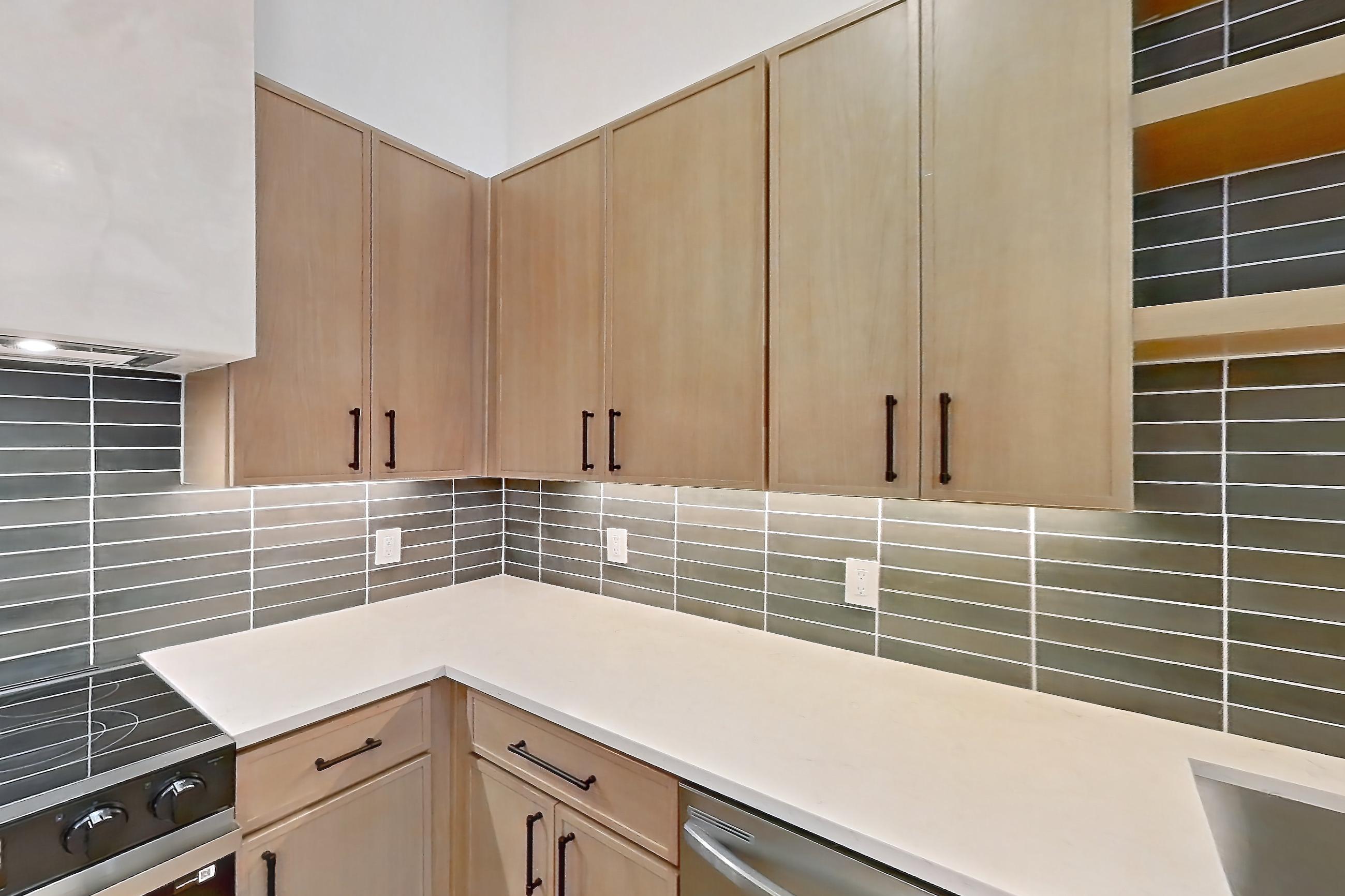 Kitchen with dishwasher, electric range, light countertops, light stone countertops, light wood-finish flooring, oven/range, range hood, and stainless steel appliances, Apartment 1108 at Cortland Galleria