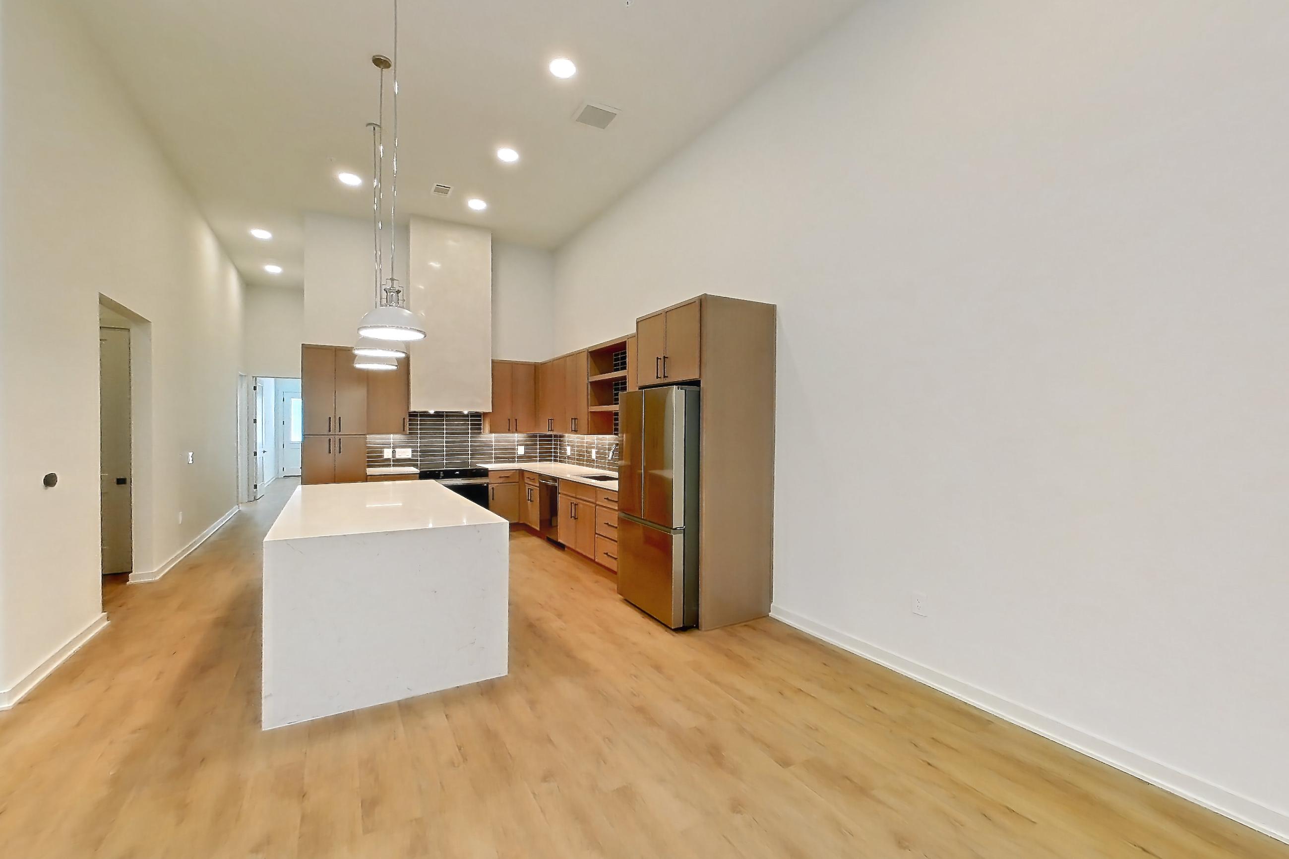 Living room with light countertops, light stone countertops, light wood-finish flooring, refrigerator, and stainless steel appliances, Apartment 1108 at Cortland Galleria