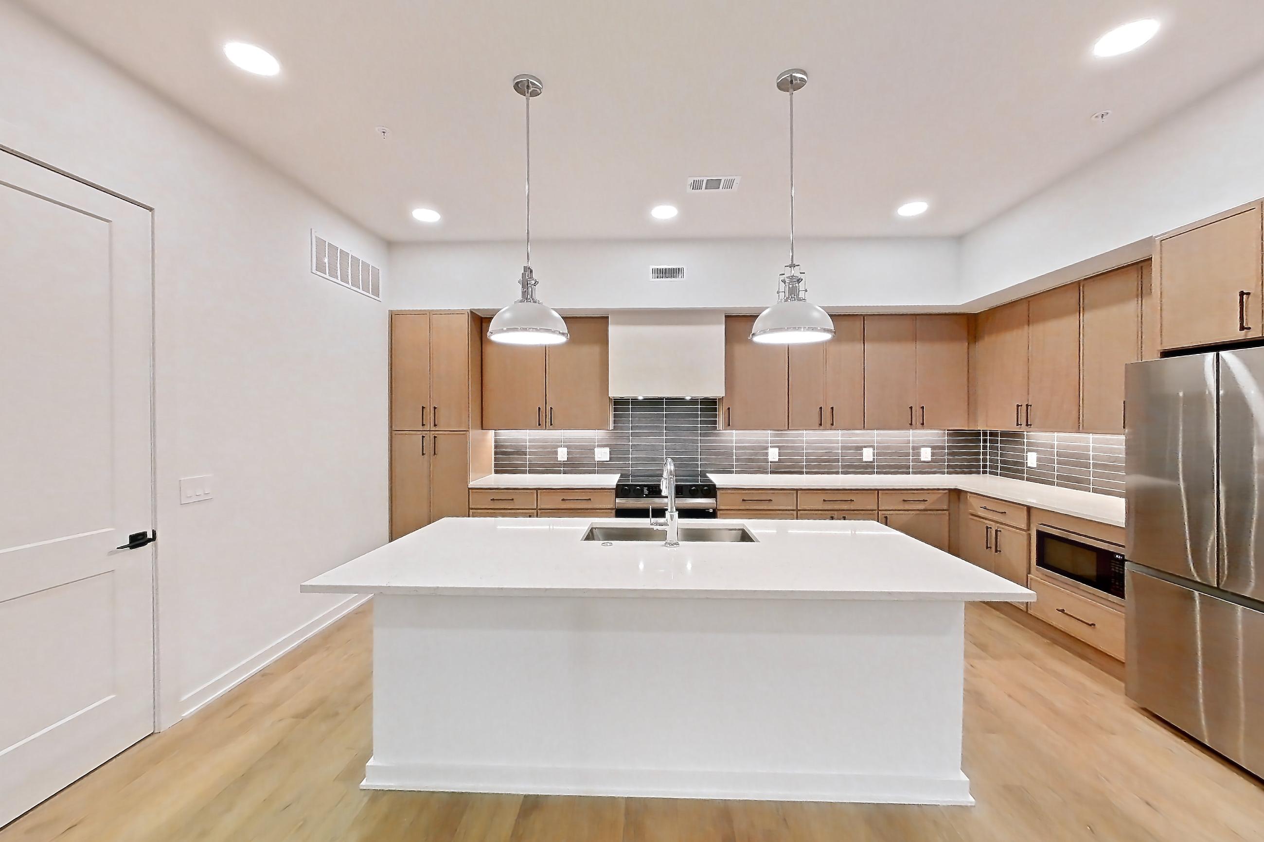 Dining room with black appliances, built-in microwave, electric range, kitchen island, light countertops, light stone countertops, light wood-finish flooring, microwave, oven/range, refrigerator, and stainless steel appliances, Apartment 1105 at Cortland Galleria