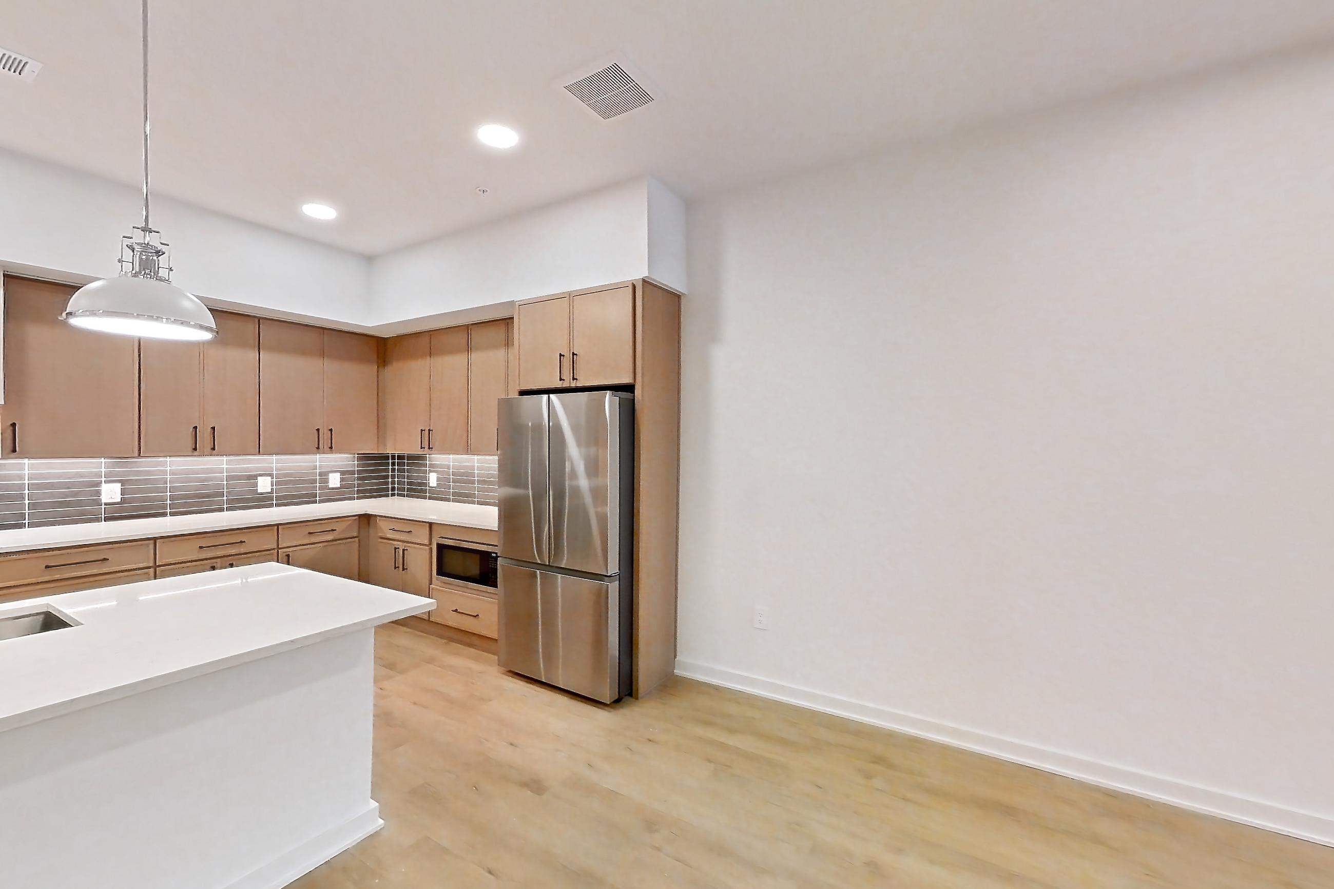 Dining room with black appliances, built-in microwave, electric range, kitchen island, light countertops, light stone countertops, light wood-finish flooring, microwave, oven/range, refrigerator, and stainless steel appliances, Apartment 1105 at Cortland Galleria