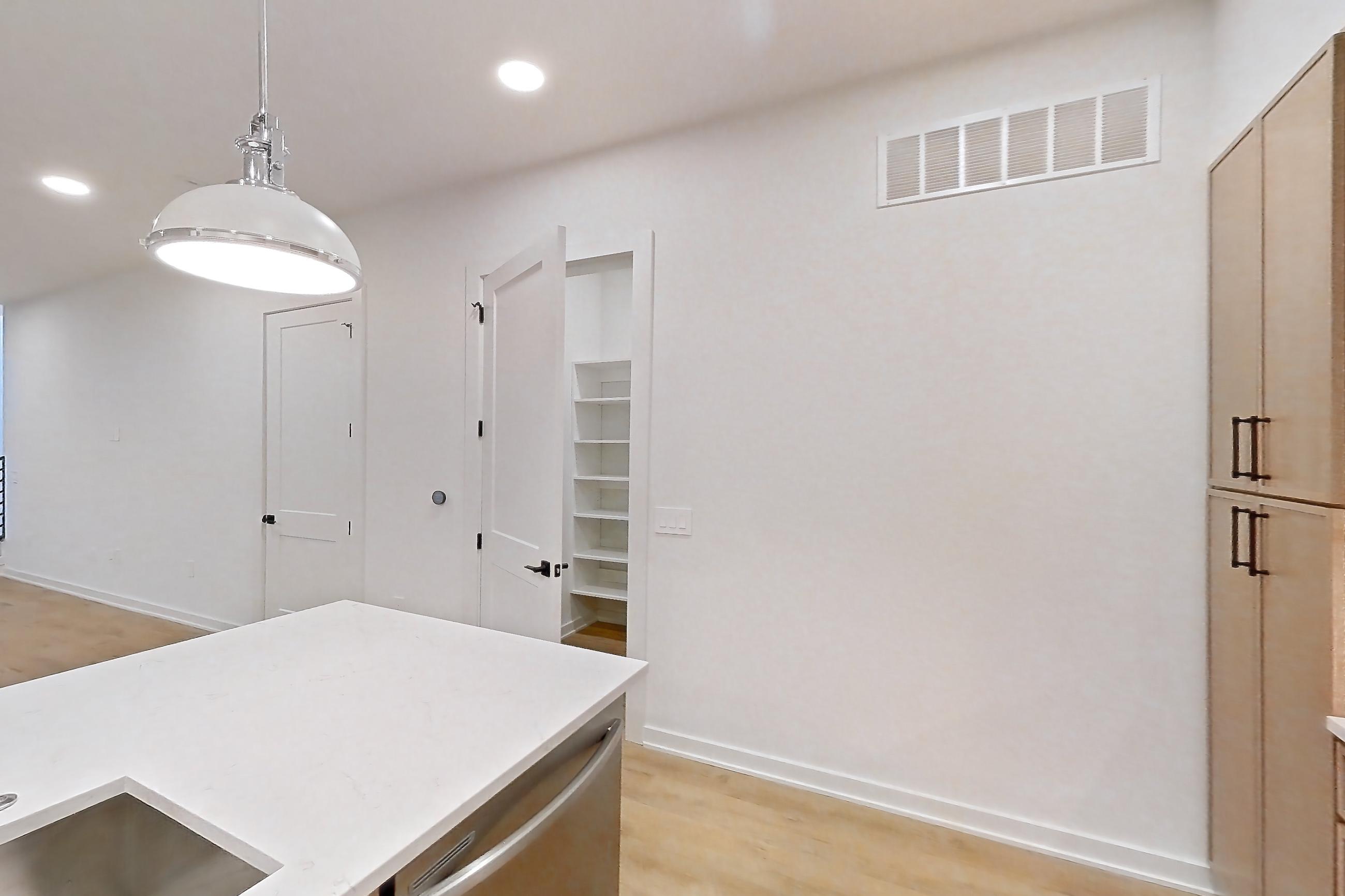 Kitchen with built-in microwave, dishwasher, kitchen island, light countertops, light stone countertops, light wood-finish flooring, microwave, oven/range, refrigerator, and stainless steel appliances, Apartment 1105 at Cortland Galleria