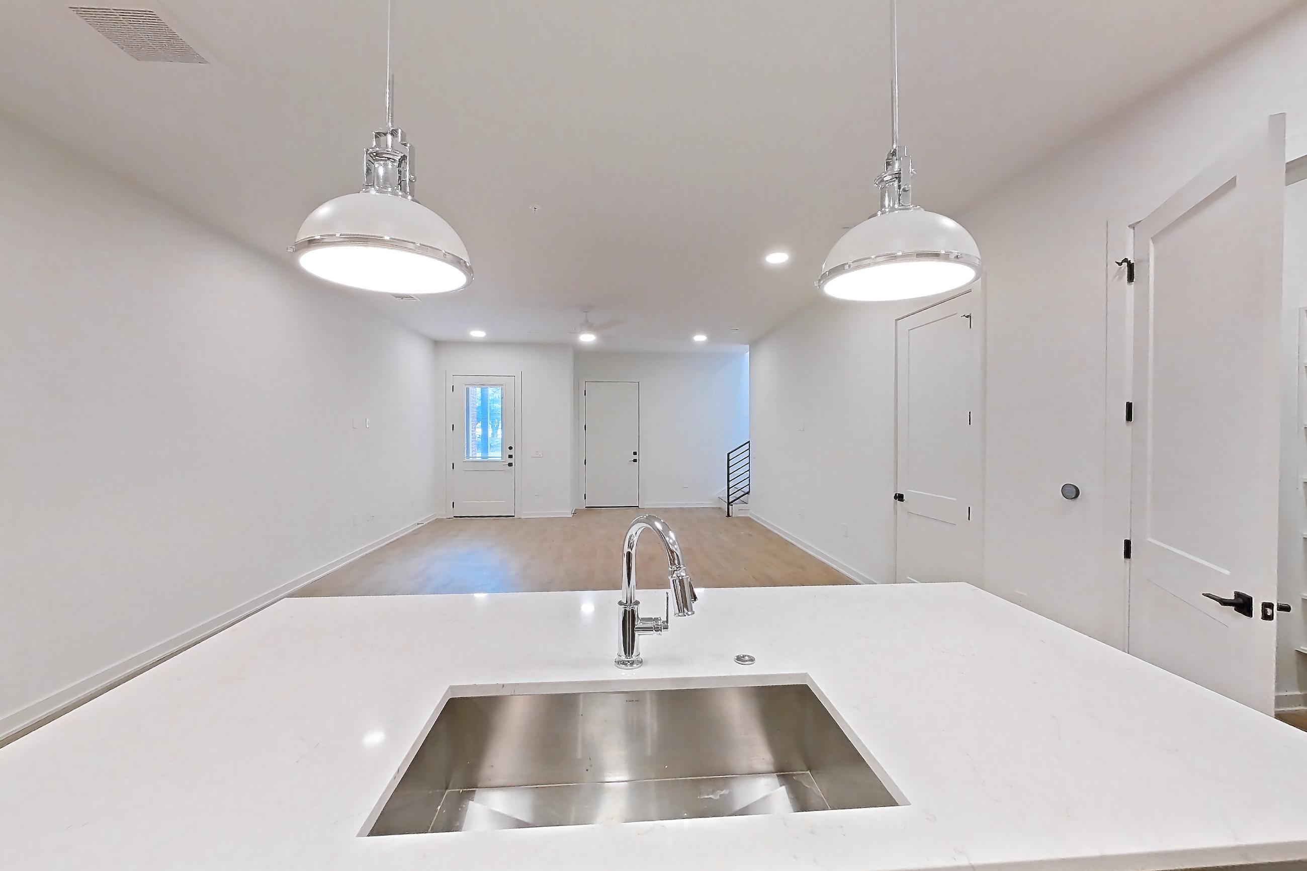 Kitchen with built-in microwave, dishwasher, kitchen island, light countertops, light stone countertops, light wood-finish flooring, microwave, oven/range, refrigerator, and stainless steel appliances, Apartment 1105 at Cortland Galleria