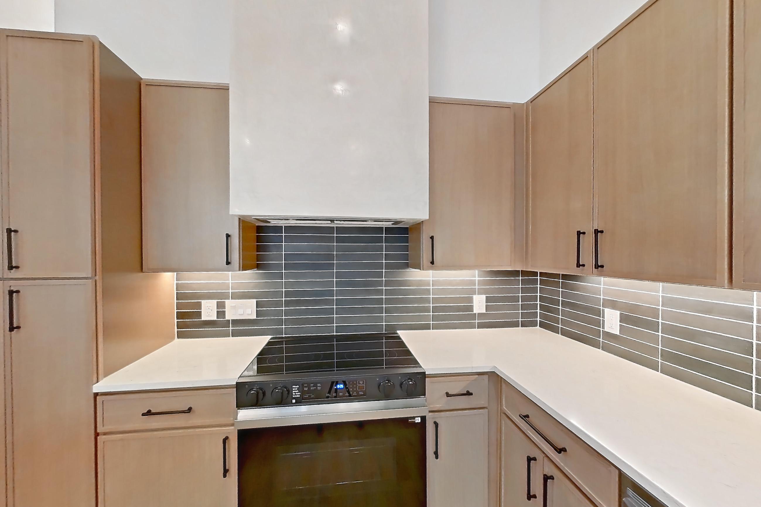 Kitchen with dishwasher, electric range, light countertops, light stone countertops, light wood-finish flooring, oven/range, and stainless steel appliances, Apartment 1109 at Cortland Galleria