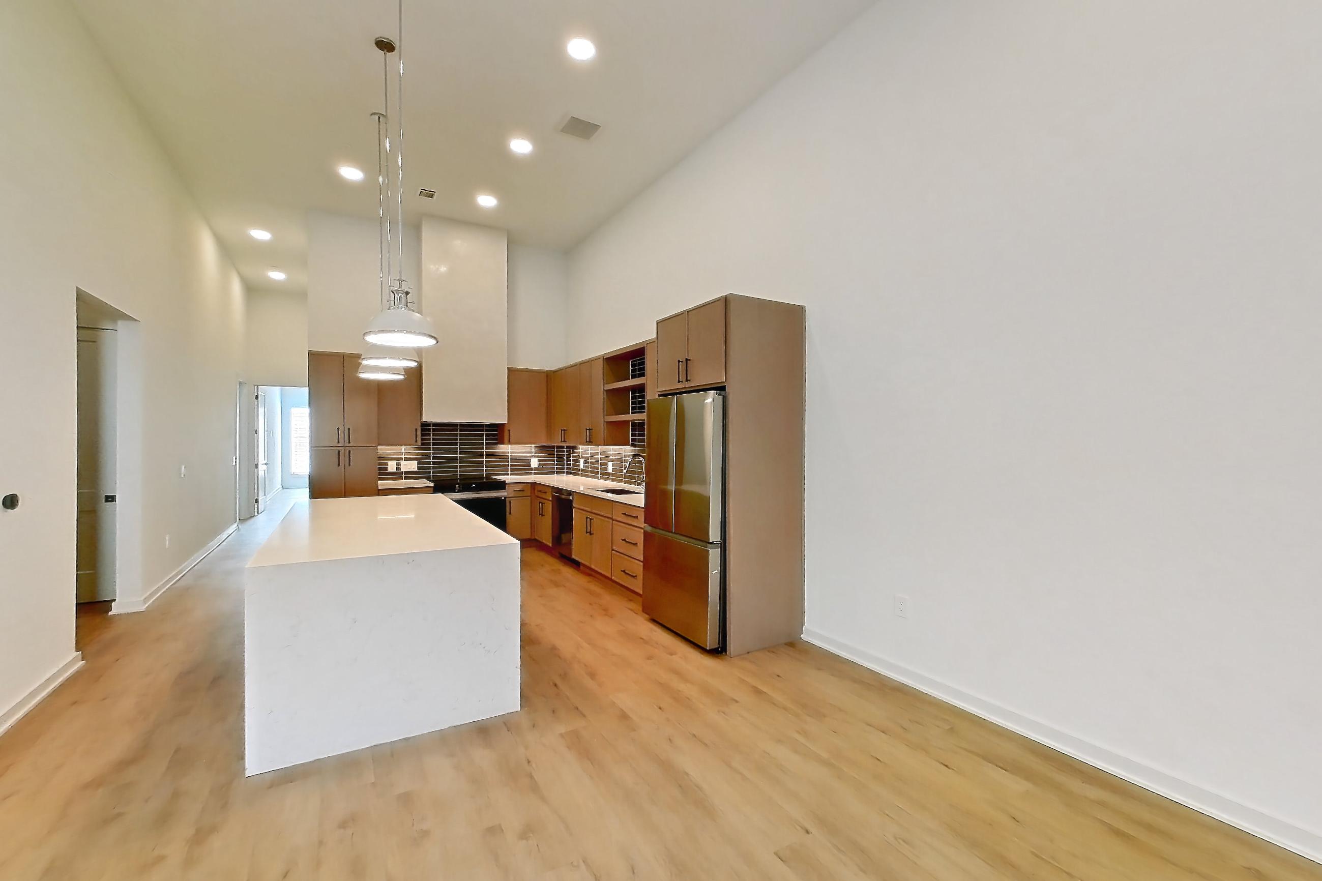 Living room with dishwasher, light countertops, light stone countertops, light wood-finish flooring, refrigerator, and stainless steel appliances, Apartment 1109 at Cortland Galleria