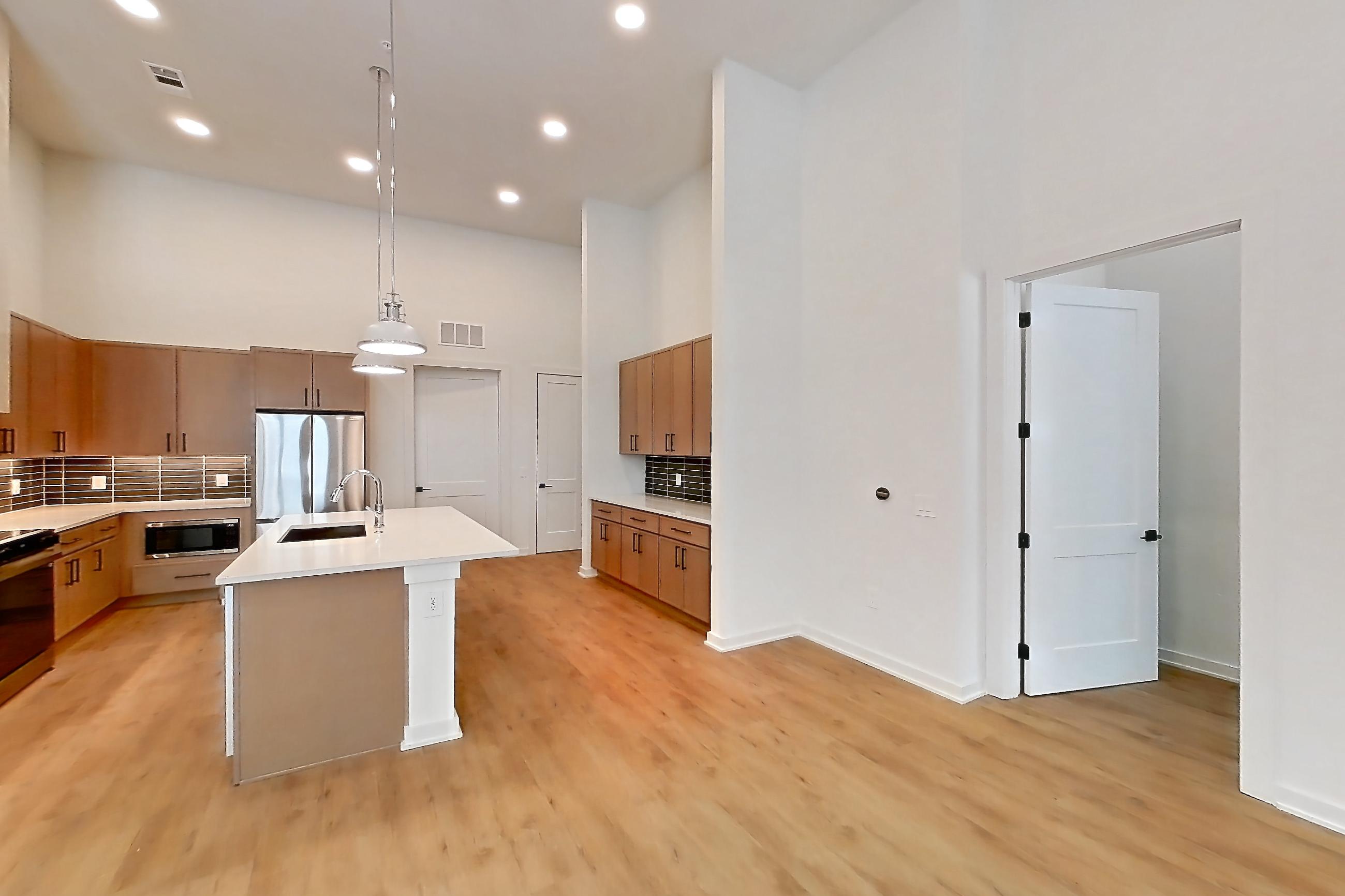Living room with electric range, kitchen island, light countertops, light wood-finish flooring, microwave, and stainless steel appliances, Apartment 1117 at Cortland Galleria