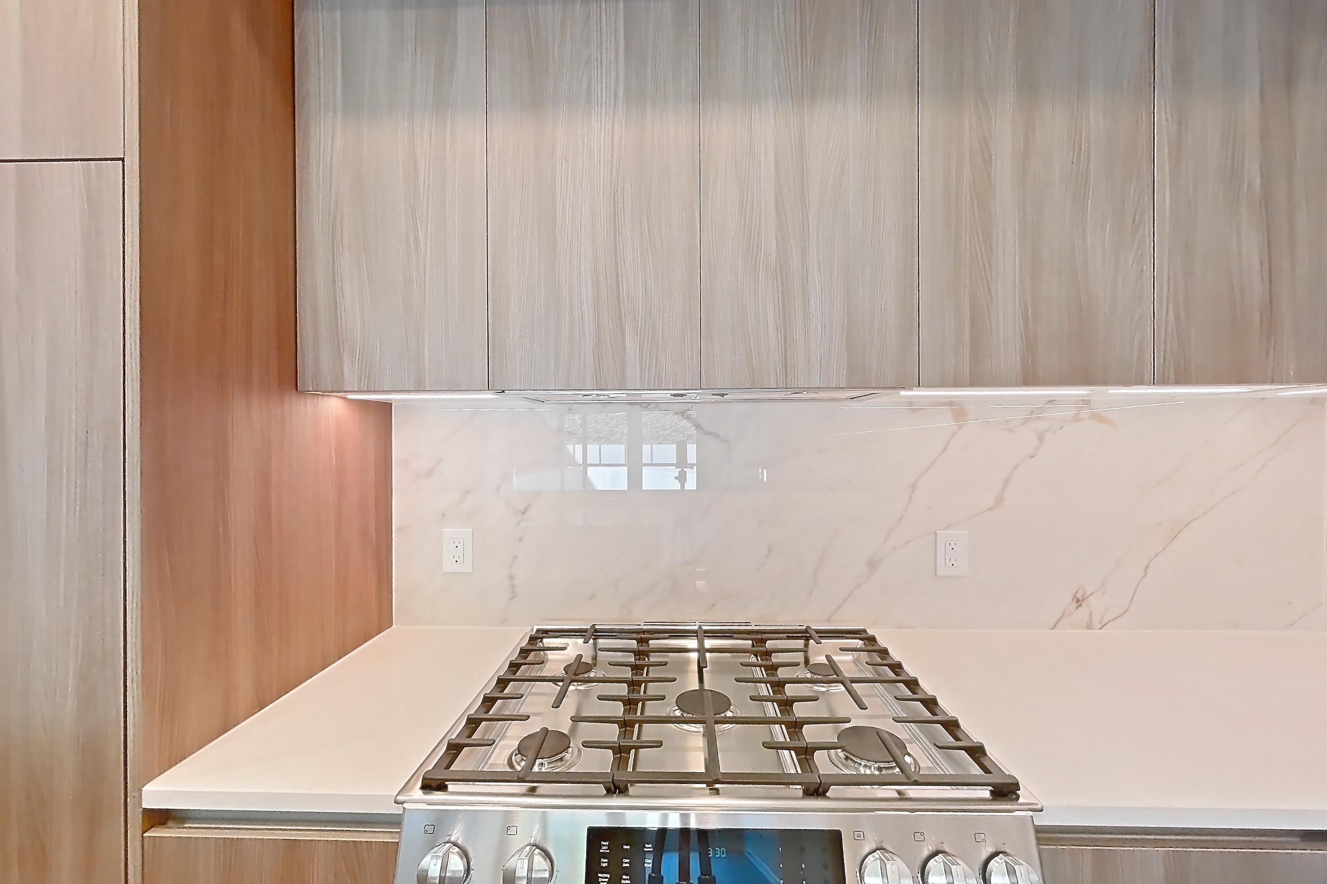 Kitchen with gas range, light stone countertops, light wood-finish flooring, oven/range, and stainless steel appliances, Apartment 0112 at Aerie