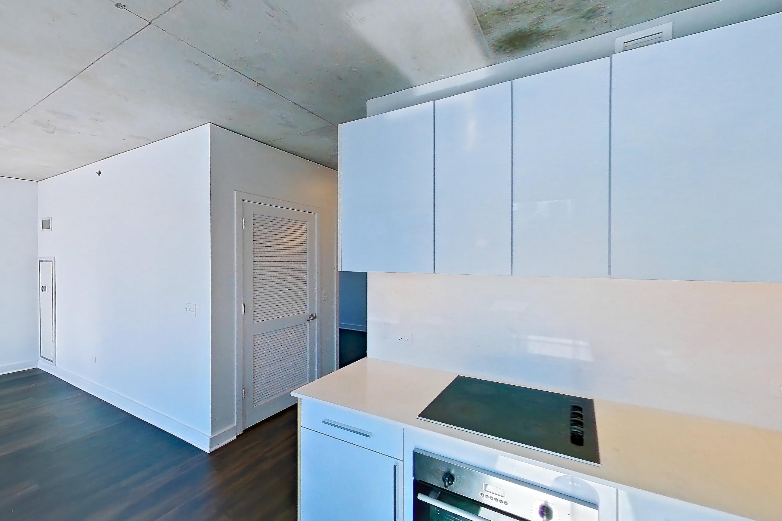 Kitchen with black appliances, cooktop, dark wood-finish flooring, electric cooktop, light stone countertops, light wood-finish flooring, oven/range, refrigerator, skyline view, and stainless steel appliances, Apartment 2302 at 220 WIL